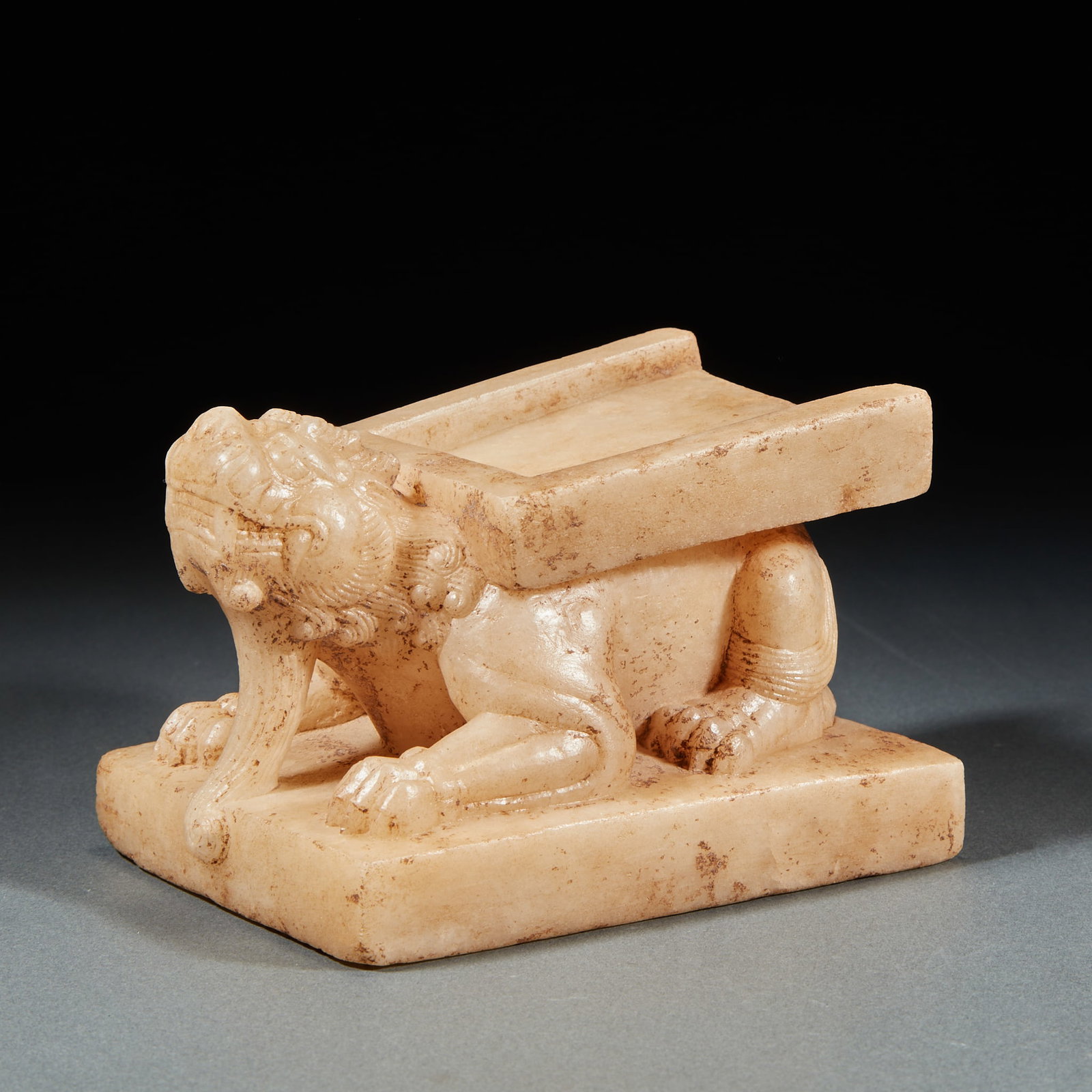 White marble beast inkstone: White marble texture, the beast is prone on the square base. The animal's head leans forward, its beard hangs down, its mane is finely carved, its limbs curl up, and its feet depict claw lines. The