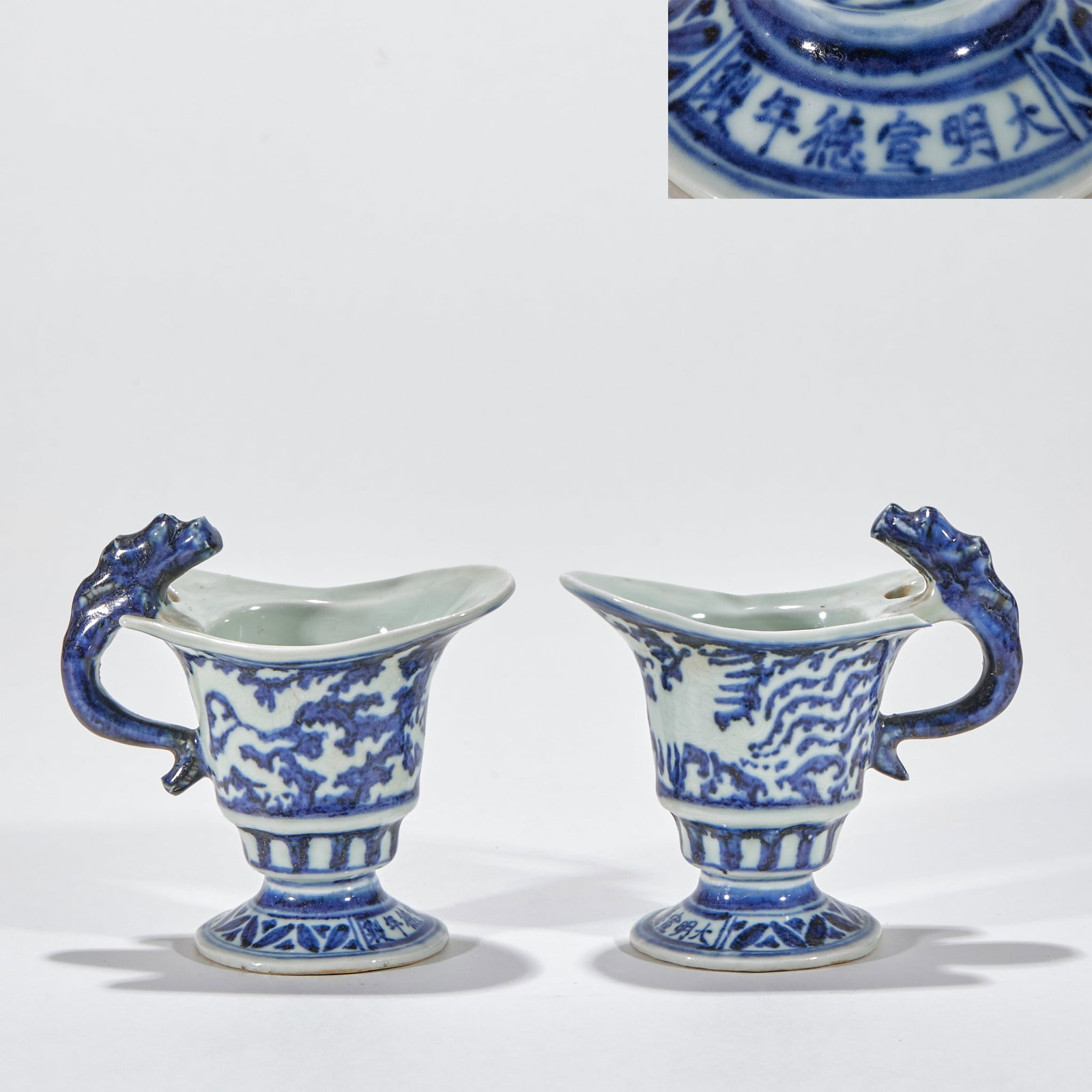 Daming Xuande Annual Blue and White Dragon Cup Pair: Paired porcelain cups, the cup mouth is in the shape of a flower mouth, and one side is molded with a dragon head-shaped handle. The outer wall of the cup is painted with dragon and phoenix patterns