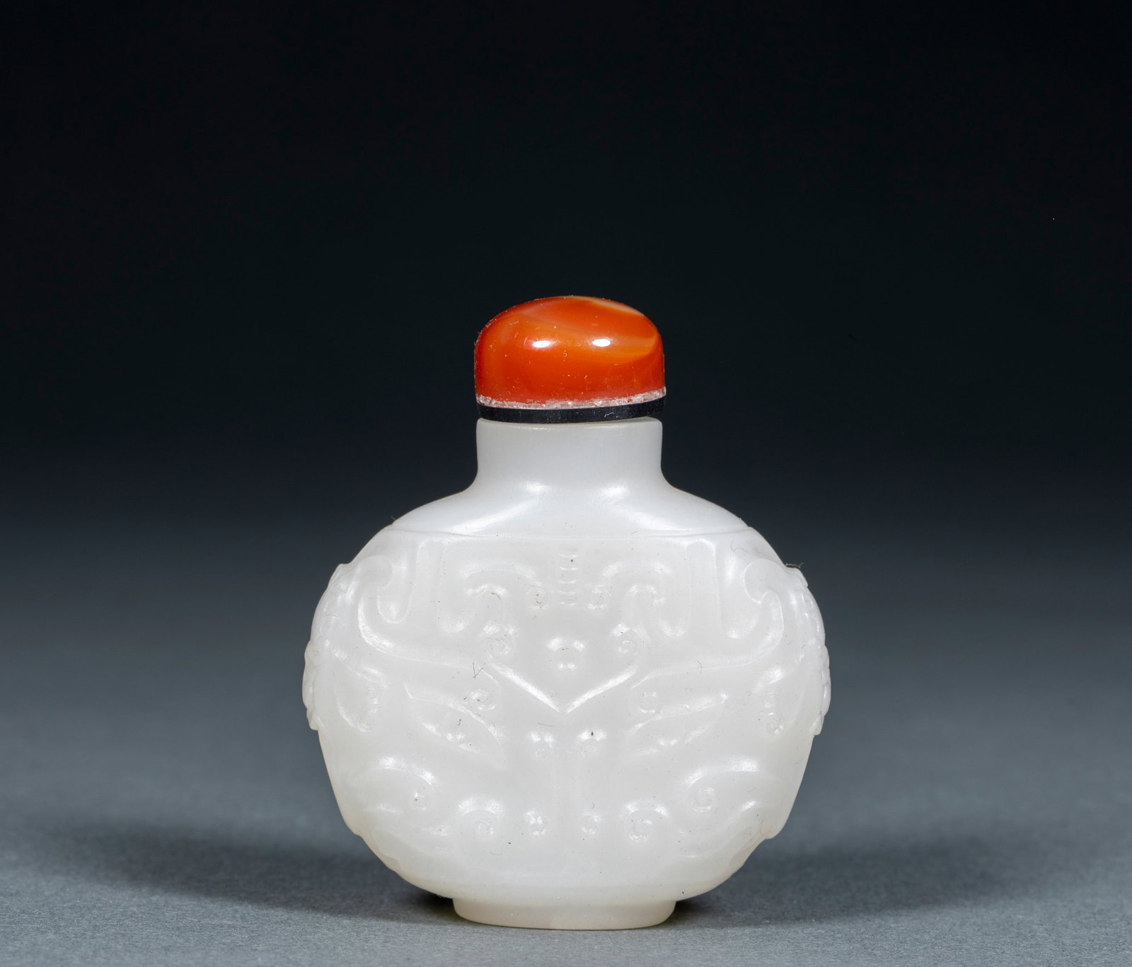 Hotan Baiyu Taotie Snuff Bottle: White jade texture, the vessel is a flat round bottle, with a straight neck, a shoulder, a flat abdomen and a shallow circle. The ampulla is decorated with embossed animal face patterns on both sides,