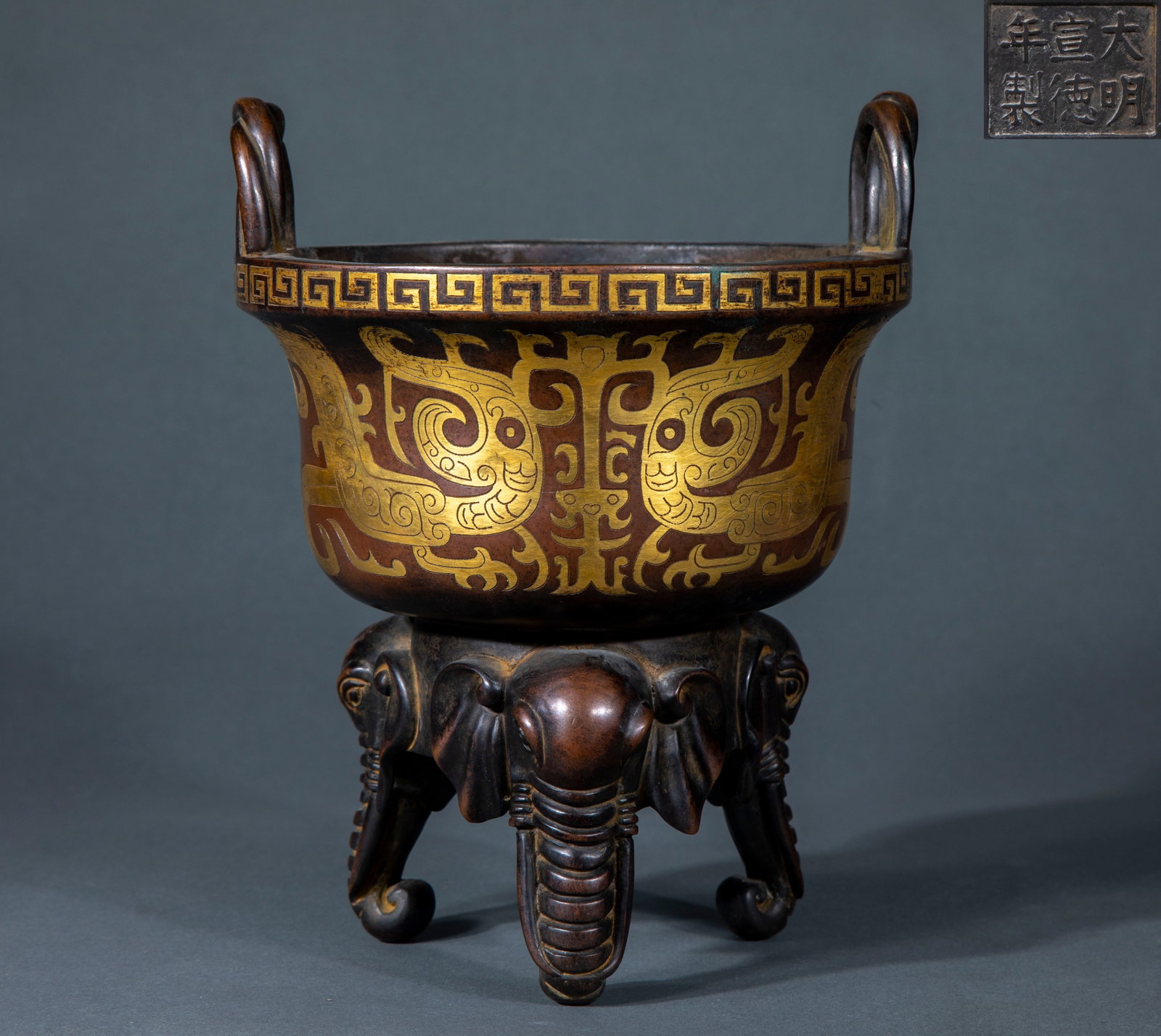Ming Xuande painted a golden dragon with three elephant feet and a fragrant incense burner.: The copper furnace body has a pair of rope-patterned ears along the mouth edge, and the mouth edge is decorated with back-patterned edges. The furnace belly is carved with antique phoenix patterns,