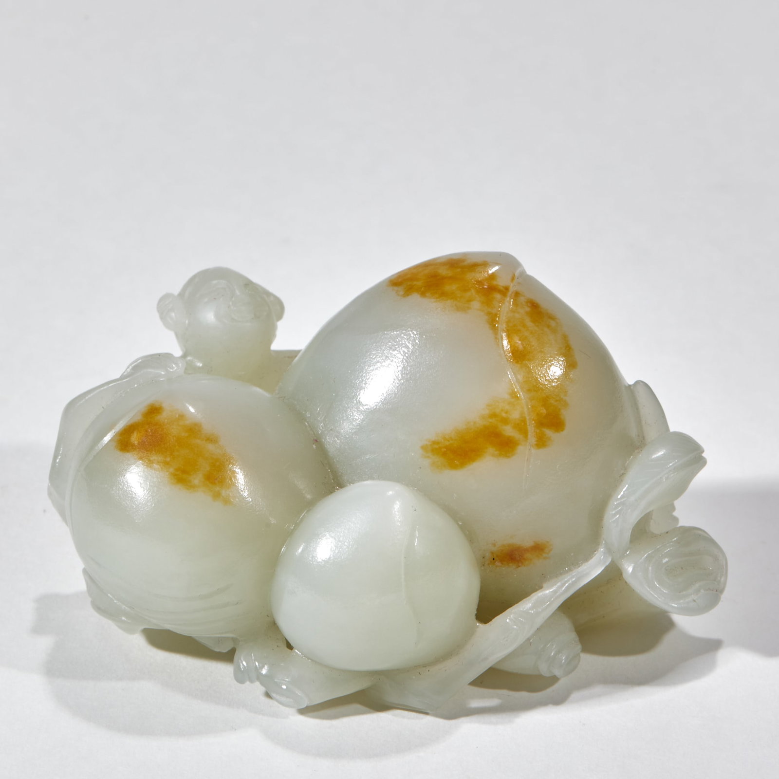 Hotan Jade Fairy Birthday: Jade is blue and white jade with natural golden jade skin on the surface. There are three longevity peaches in the size of a round carving. The peach body is made of jade skin, and the branches are