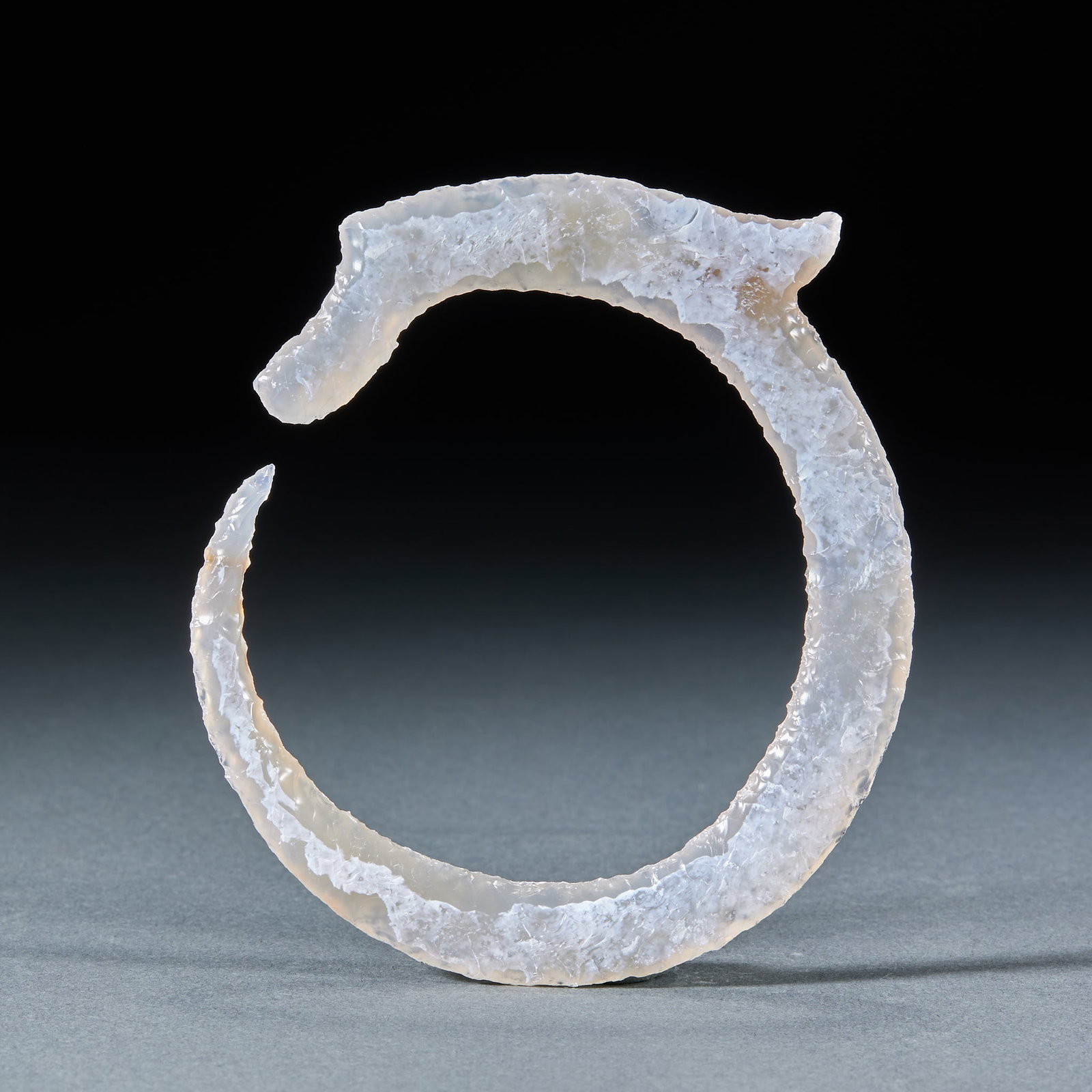 Agate biting tail dragon: The agate carved a C-shaped dragon, and the whole dragon was shaped like a C-shaped ring opening. The faucet is carved briefly, the surface of the device is covered with polishing marks, and the agate