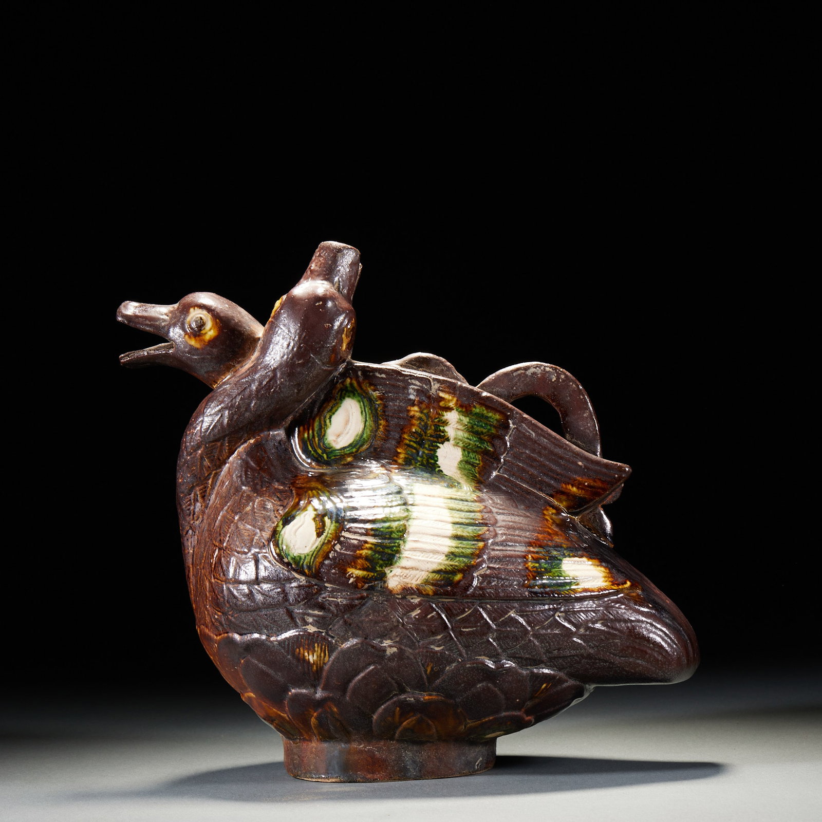 Tri-colored porcelain mandarin ducks are fragrant.: The whole body is shaped like a mandarin duck, with a spout at the mouth and a handle on the back. The body is painted with three colors of brown, green and white, and the feather texture is depicted 