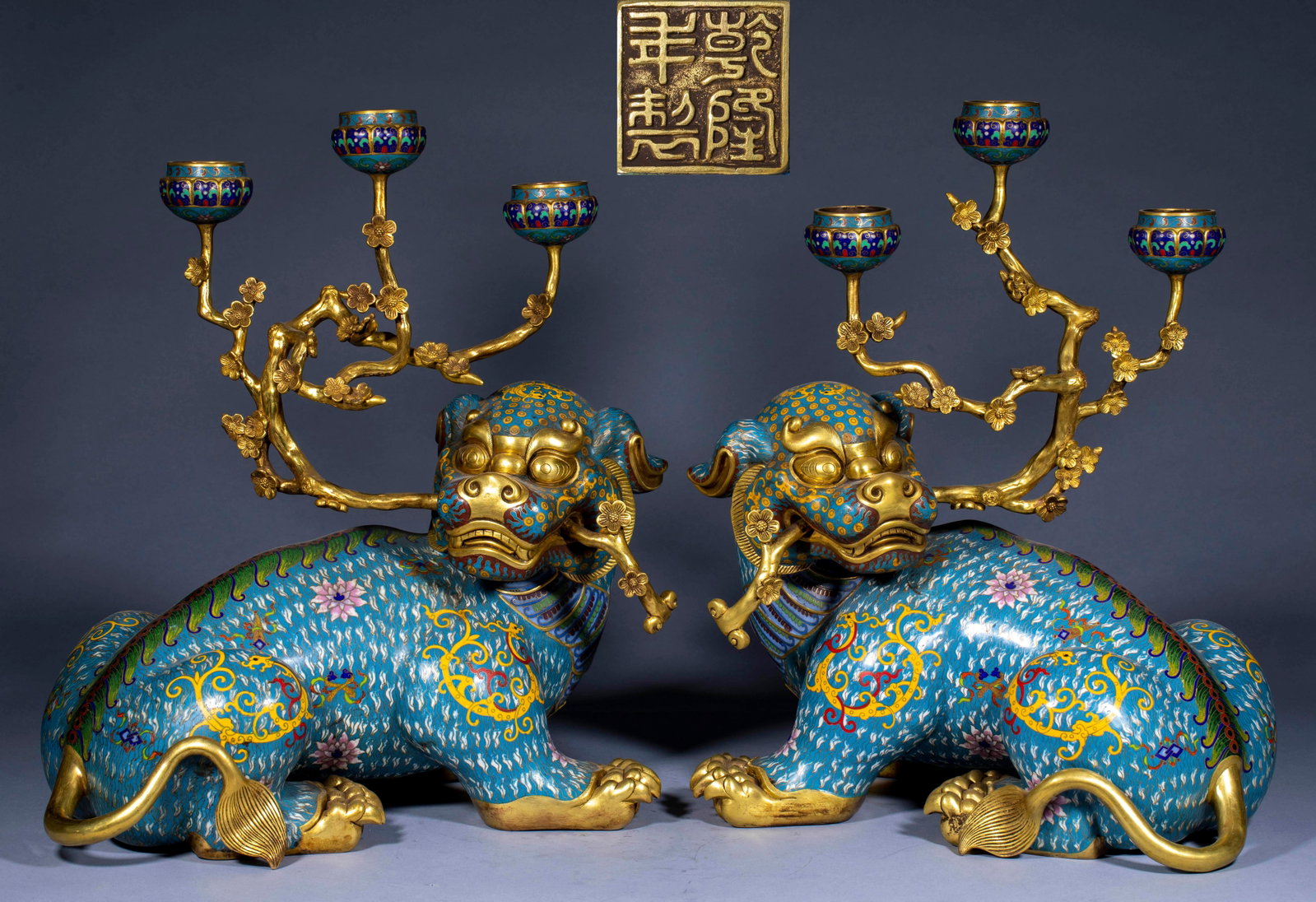 A pair of Cloisonneenamel double lion candlesticks in Qianlong year.: A pair of recumbent Swiss animals, whose bodies are made of light blue cloisonne enamel, are painted with flowers and grass patterns, and their facial features, paws and tails are all gilded. Rui beas