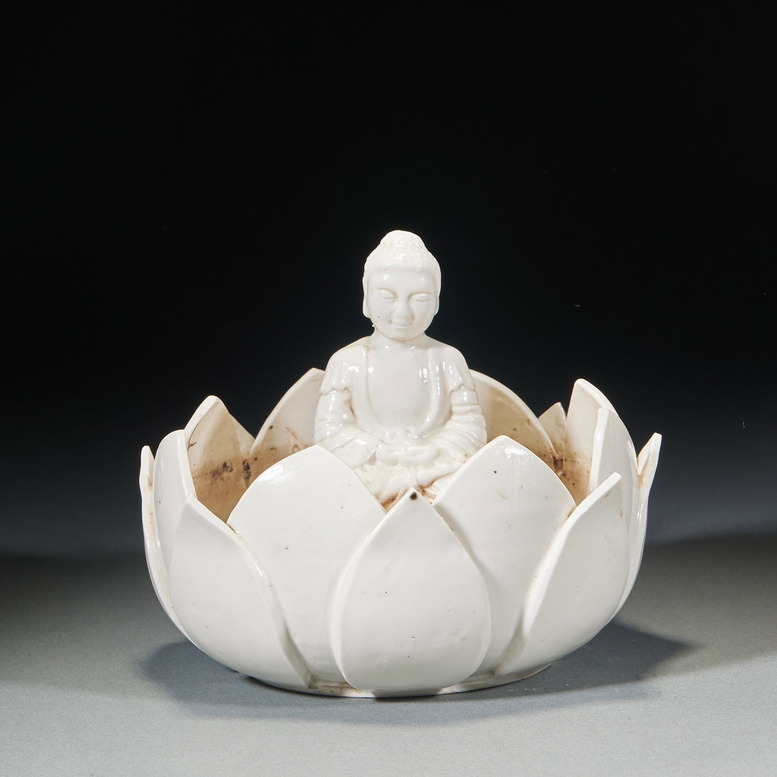 White porcelain lotus Buddha statue of Sakyamuni: The overall lotus shape, multi-petal lotus petals open outward, lotus petals layered clearly. Inside the lotus cavity, Sakyamuni Buddha sits, and the Buddha sits in a crouching position, his hands