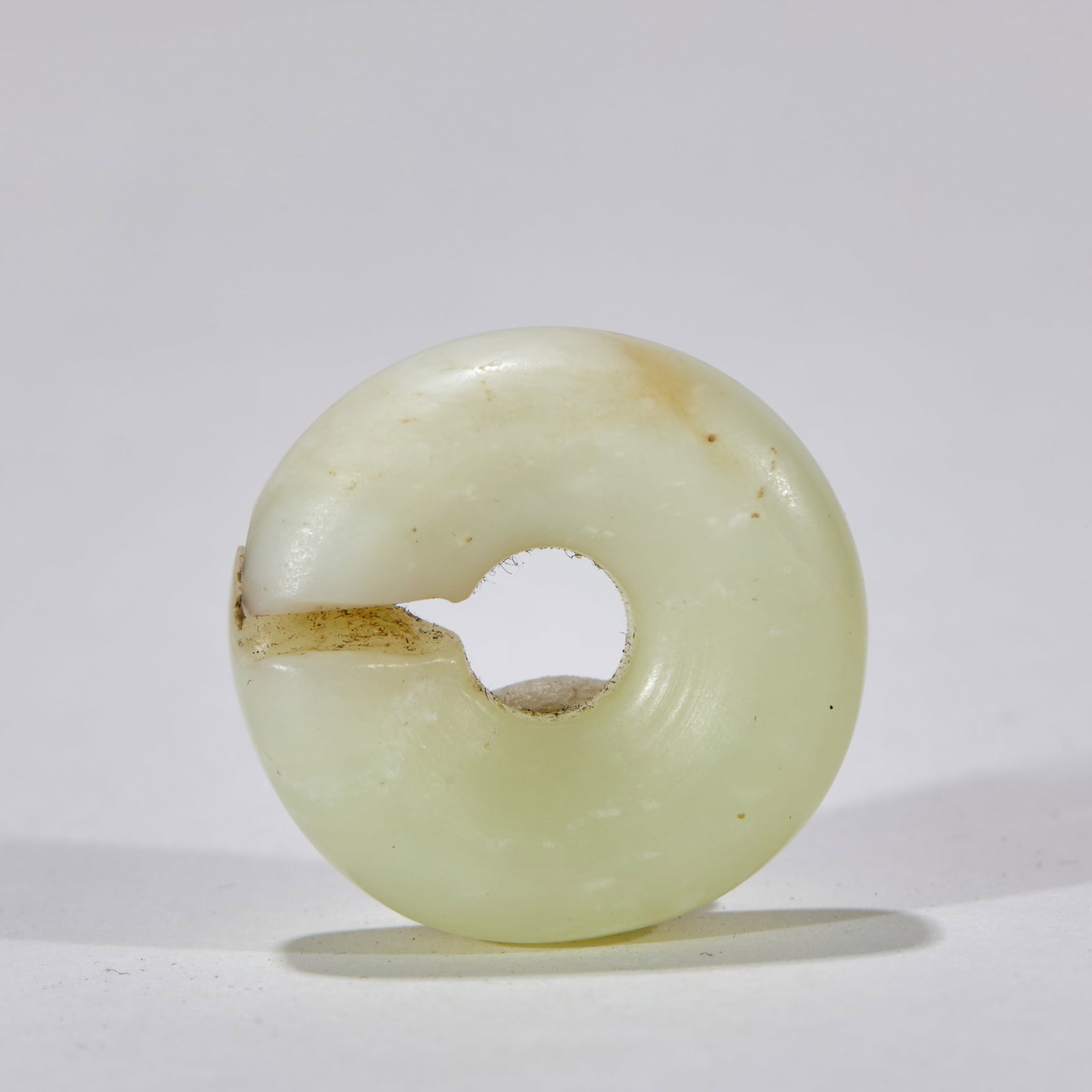 Before Ming Dynasty, Hotan Jade was short of jade.: Topaz texture, flat body, central hole, side notch. The jade color is white and yellow, with yellowish brown spots on the surface, chipping defects at the notch, polishing marks on the hole edge and