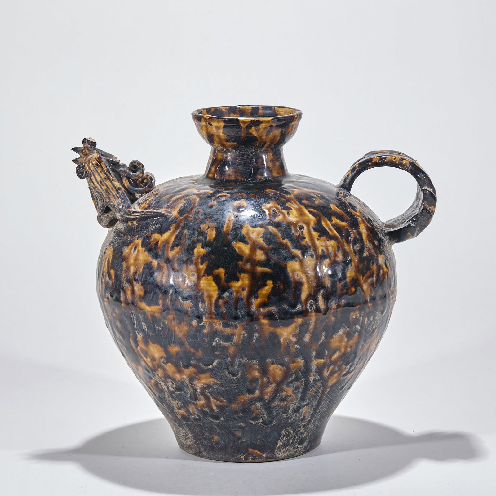 Jizhou kiln tortoise shell glazed phoenix head holding pot: The pot has a mouth, a neck, a round belly and a lower abdomen. Plastic chicken head flows on one side, and the outline of chicken head is clearly depicted; The other side is provided with an annular