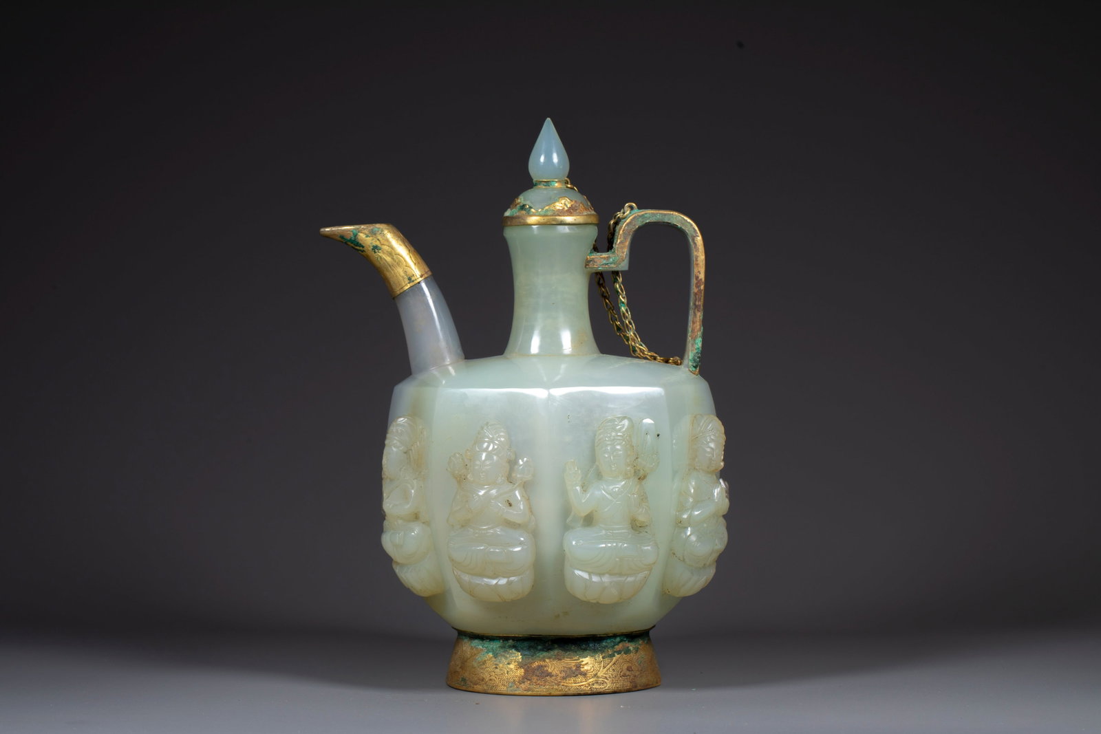 Qidan agate covered with gold and skillfully carved Buddha statue holding pot: The pot body is carved with white jade, with octagonal shape, and four statues of sitting lotus bodhisattvas are embossed on the outer wall of the pot. The spout, lid, handle and bottom of the pot are