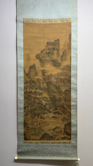 Silk manuscripts of landscape figures in Chou Ying: The vertical shaft is completely mounted, with beige shaft head. The silk book is colored, the picture is painted with mountains and mountains, and the mountains are shrouded in clouds. There are pavi
