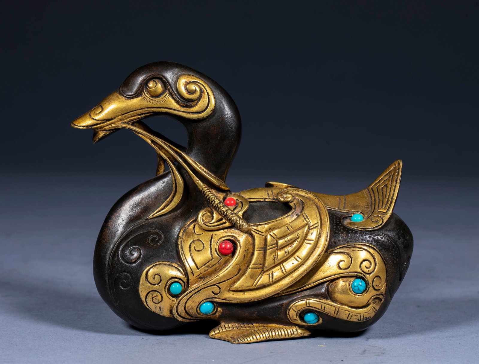 Bronze gilded duck ornaments: Copper, the body is dark brown and bronze, and the decorative parts are gilded. The whole duck is in the shape of a duck with a branch in its mouth and a curled body. The wings and tail are carved