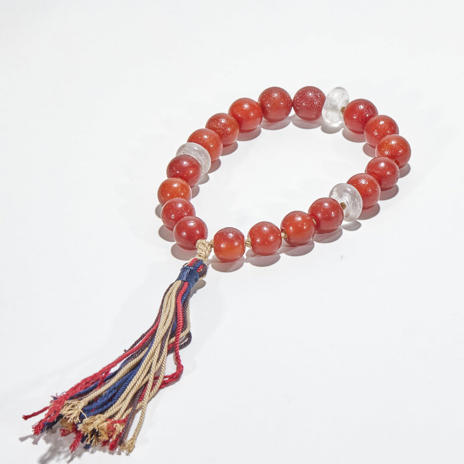 Agate with Crystal Beads Handheld: It is made of eighteen red agate beads, and the surface of agate is covered with fine ice cracks. There are two white crystal beads between them, and the ends are connected with blue, red and beige