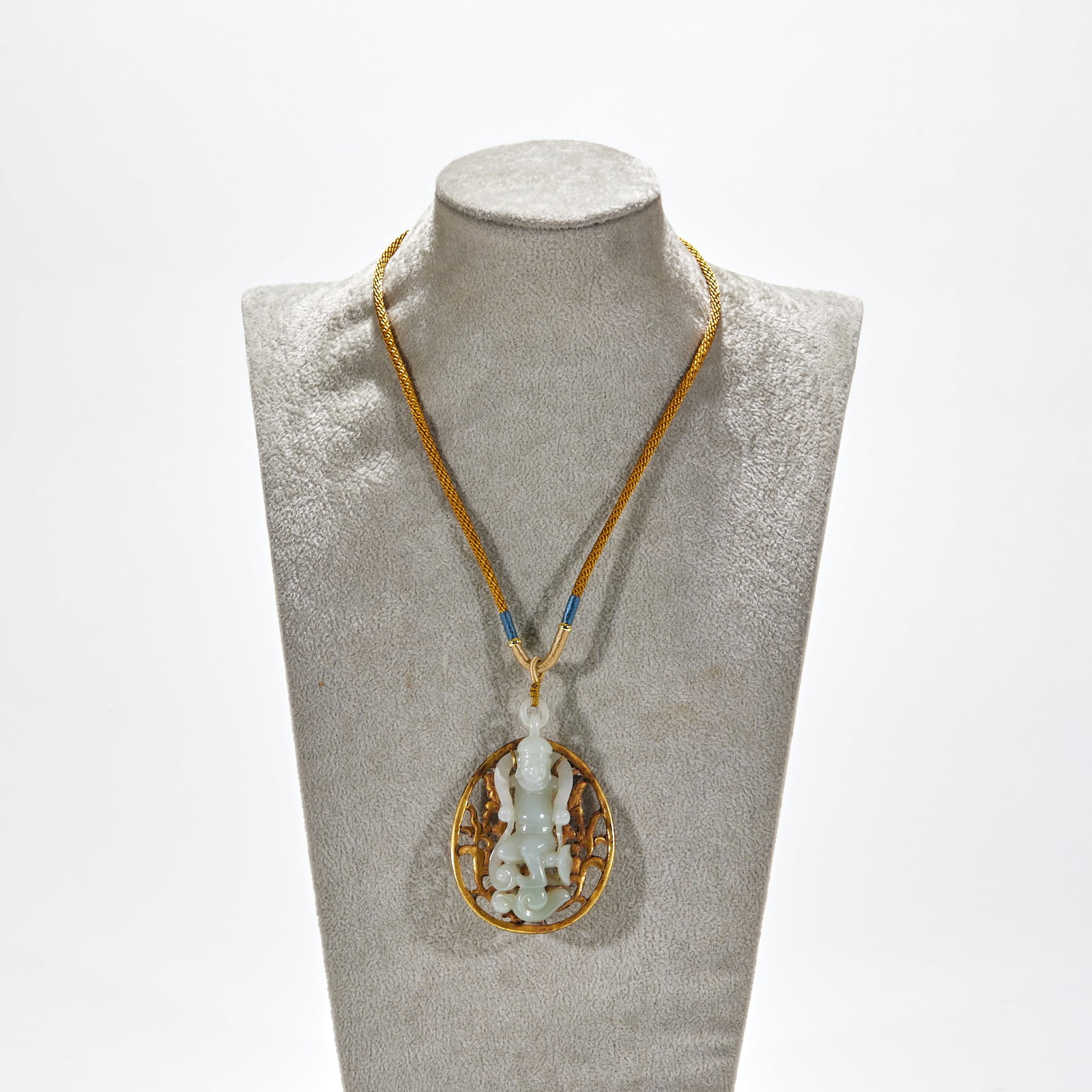 Bronze-gilded and gold-clad Hu Ren pendant: With braided gold rope chain, decorated with blue beads. The main body is an oval gold-plated outer frame, in which white jade carvings are hollowed out and inlaid, and a three-dimensional boy statue 