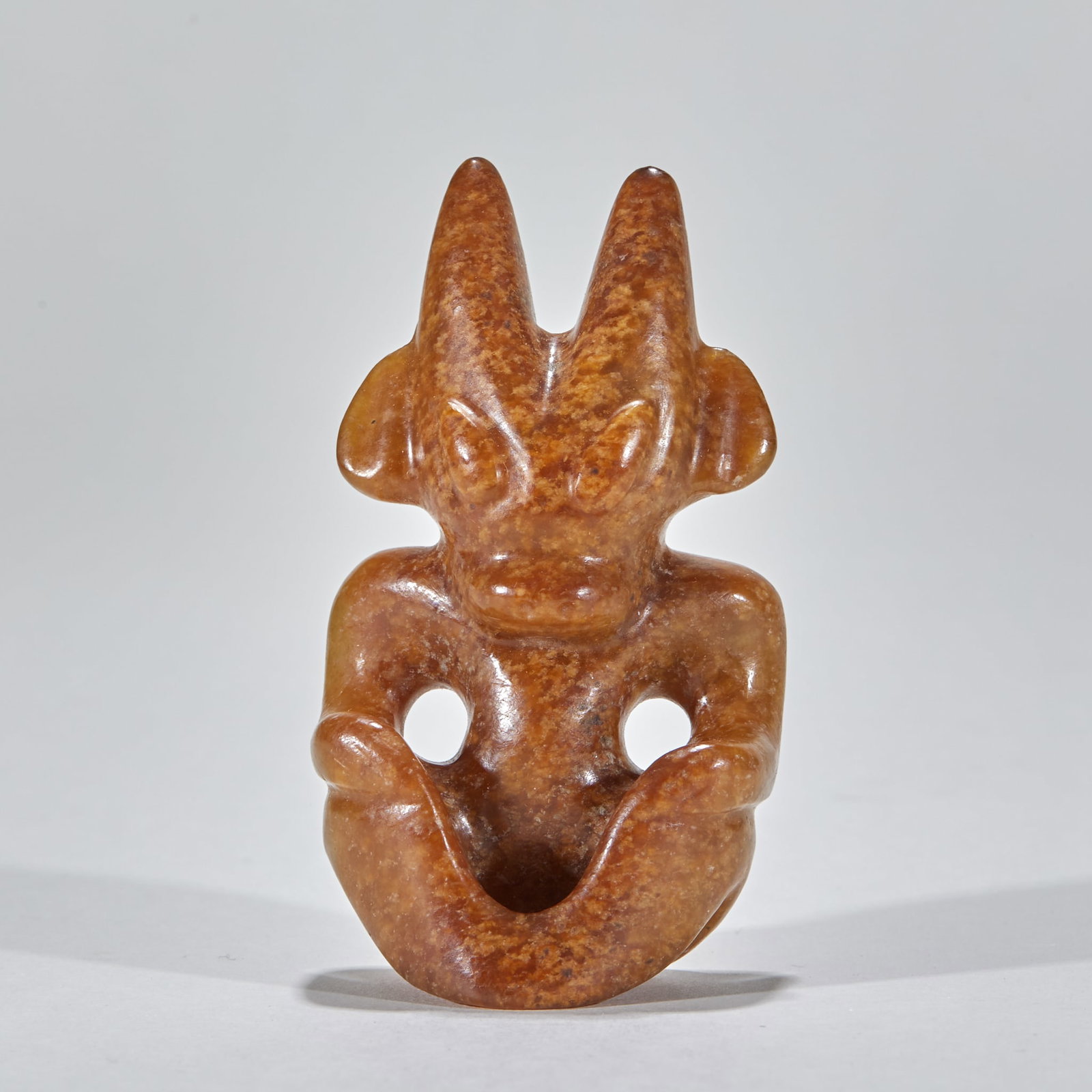 Jade sun god before Ming dynasty: Yellow-brown jade material, the whole is squatting. A pair of sharp horns are erected on the top of the head, ears are turned outwards, facial contour is simple, eyes are raised, and nose and mouth li