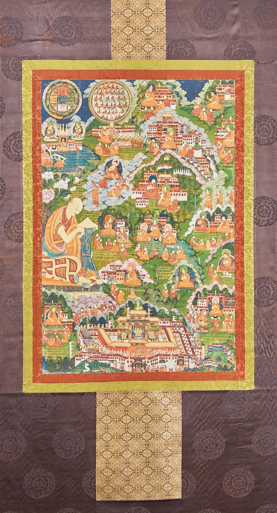 Thangka, the holy land of Tibetan Buddhist monks: The whole Thangka is mounted with brocade, with bright yellow and orange brocade frames on the outer edge in turn, and dark brown fabric with flowers on the outer substrate, with golden ribbon tapestr
