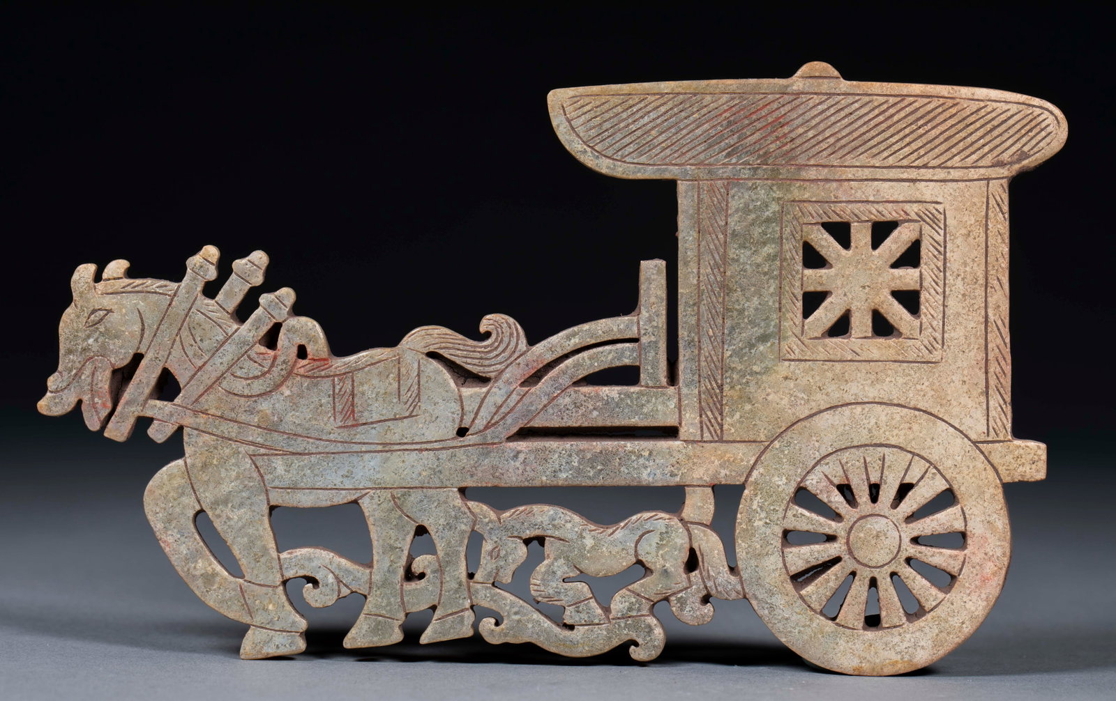 Hollow carriage jade jade: Jade, the surface is covered with weathered crimson color. Hollow carving is adopted, and the main body is a van drawn by a galloping horse. Horses strut with their heads held high, and their harnesse
