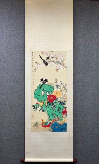 Yu Feian flower-and-bird rockery map: Paper color vertical shaft, original mounting, wooden shaft head. There are two magpies on the upper branches of the picture, a green lake stone is painted in the middle, red and yellow peonies are pl