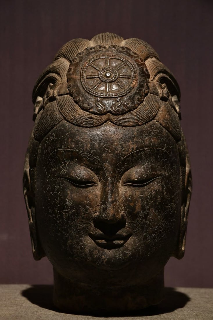 Head of Qingshi Bodhisattva: The head of a stone bodhisattva is dark. Wearing a gorgeous crown on the head, the crown is carved in the middle with a pattern of Falun, and the crown is surrounded by cirrus. Hair is portrayed in