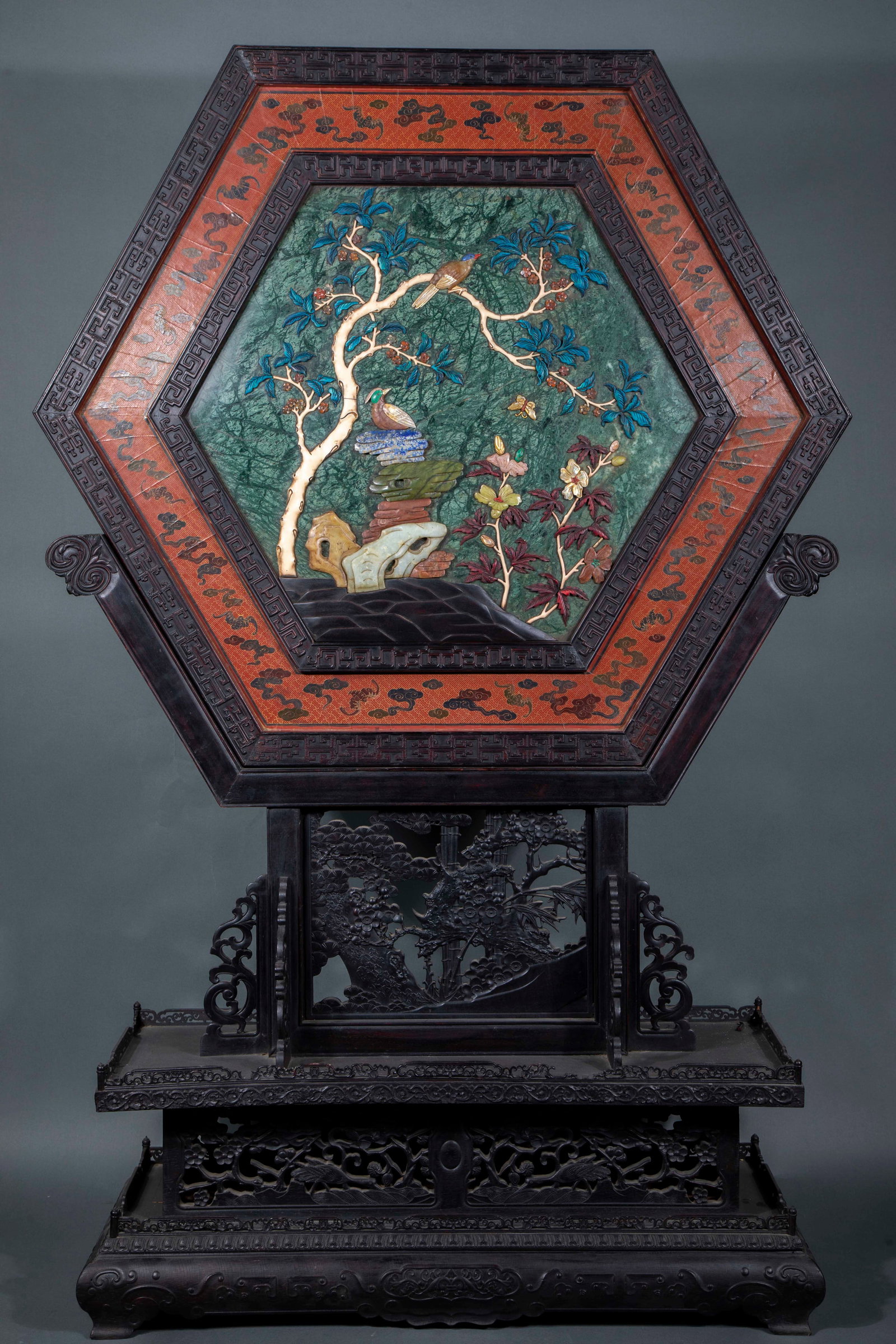 Black rosewood inlaid with 100 treasures, hexagonal flower-and-bird screen: The outer frame is dark hardwood, and the whole frame is hexagonal. The bottom plate of the screen is made of green jade, inlaid with jade, precious stones, mother-of-pearl and other materials, and