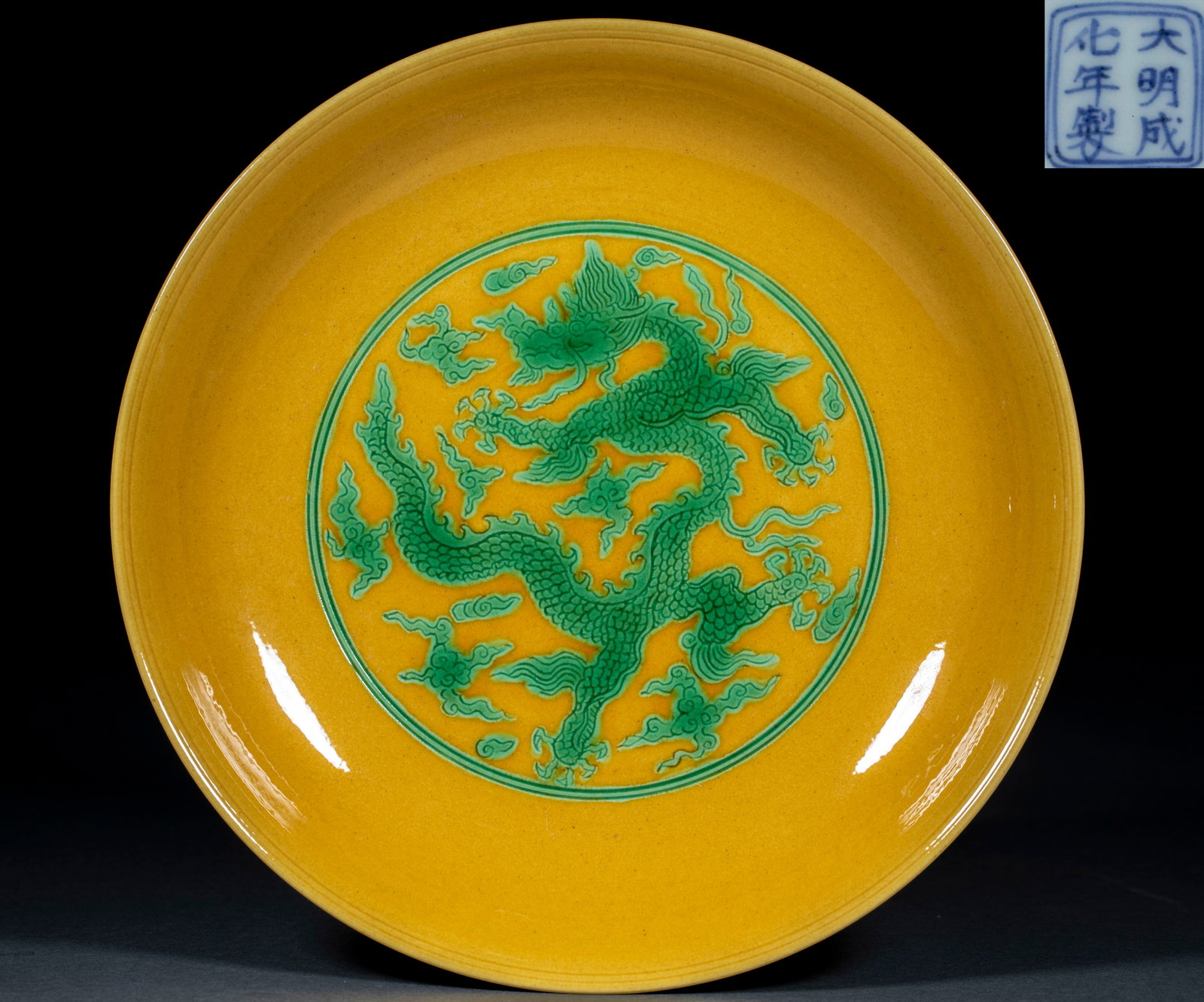 Ming Chenghua yellow glaze green colorful clouds dragon pattern appreciation plate: Open shallow dish, with bright yellow glaze inside and outside. The center of the dish is round and bright, and a five-claw dragon is carved with green color. The dragon body is surrounded by auspicio