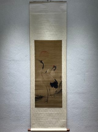 Silk edition of Lv Ji crane map: Silk vertical shaft, fully mounted. The silk color is yellow, and the picture shows two red-crowned cranes, with red sun and rocks in the background, cranes hanging up their heads, colored with ink,