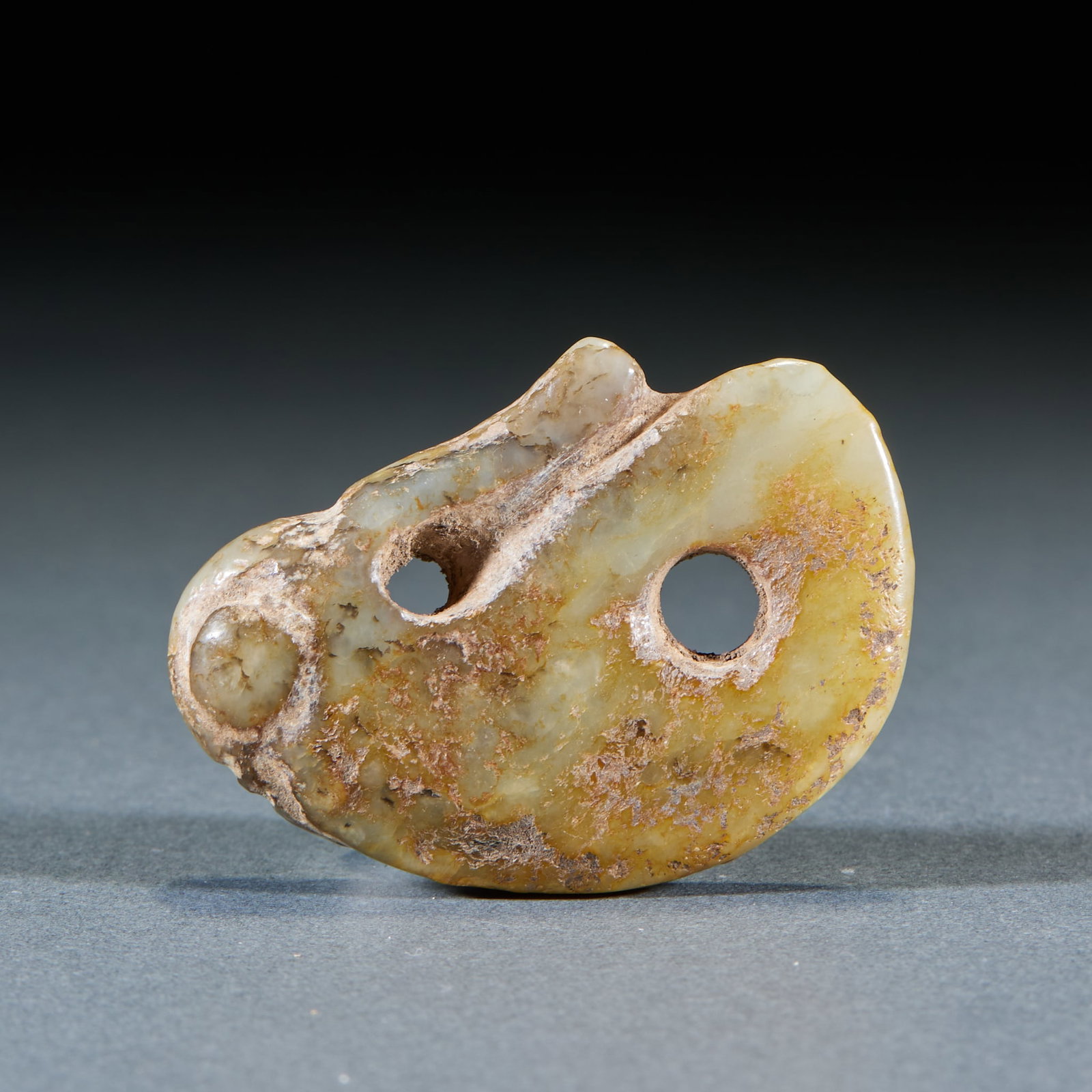 Hongshan Culture jade fish xing Pei Shi: Topaz texture, as a whole, is affected by soil erosion, with brownish yellow spots and grayish white soil erosion all over. The body of the device is conformal, with two round holes, the edge of