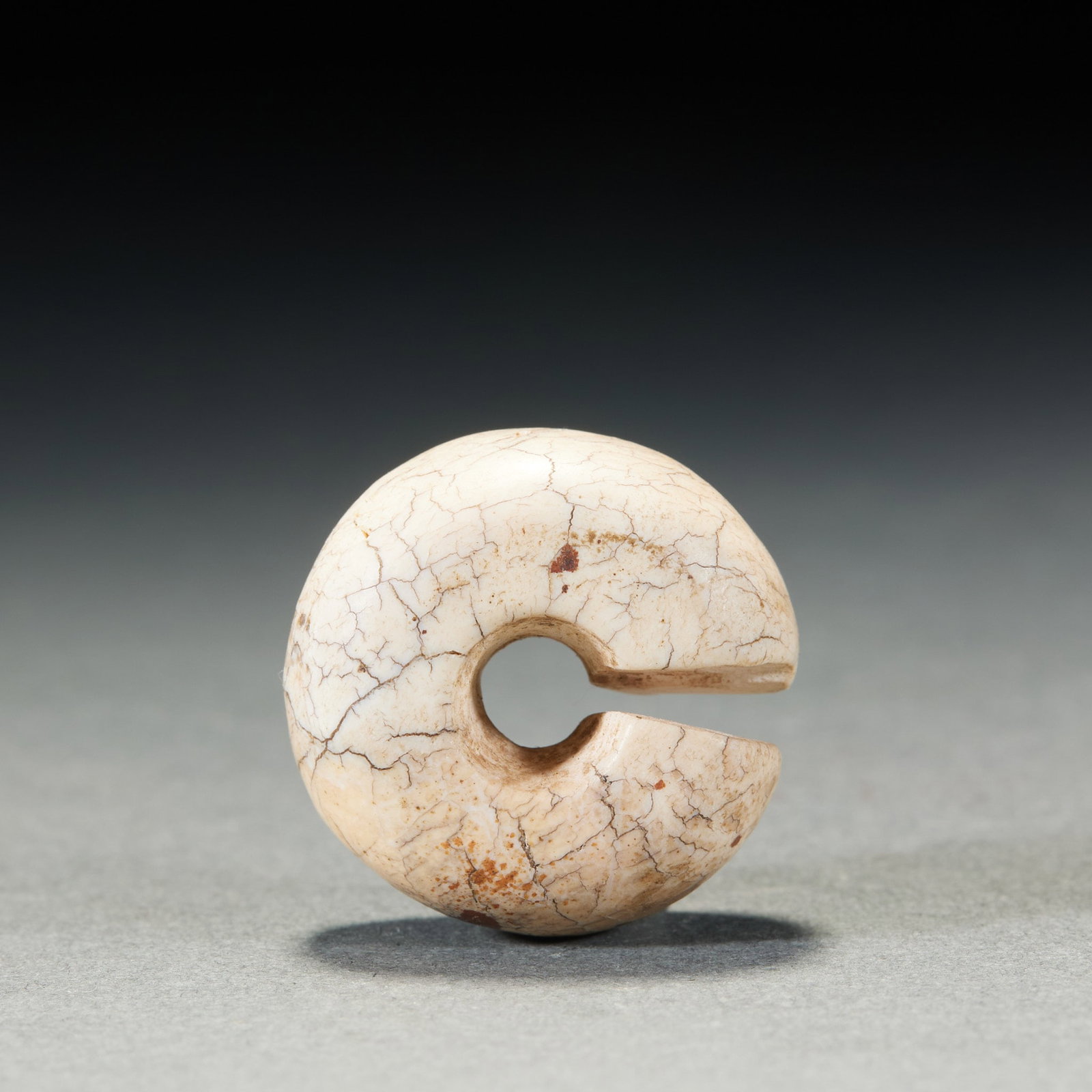 Yujun: Ring jade, the whole is chicken bone white, the whole body is covered with reticular cracking texture, and the body is scattered with reddish-brown spots. There is an opening in the ring, and a round 