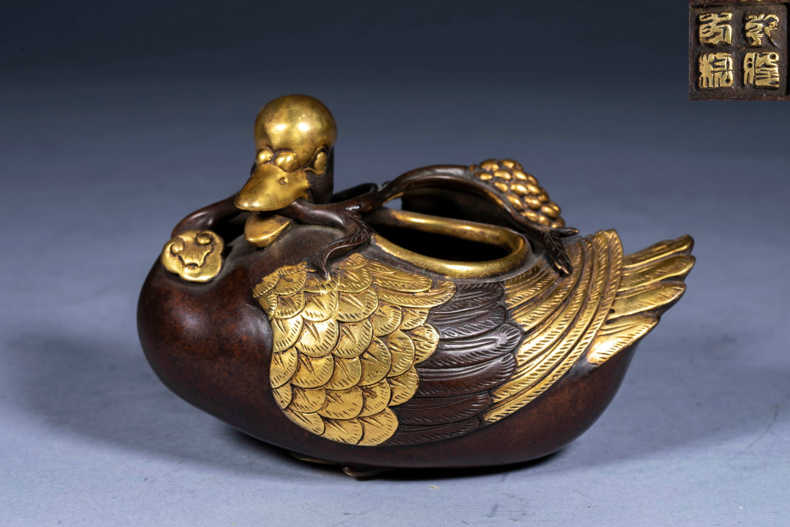 Ganlong year-old bronze gilt gold duck pen washing: The bottom is dry and long. The whole device is cast in the shape of a swimming duck. The head, neck and wings of the duck are partially gilded, and the duck body retains the original bronze color.