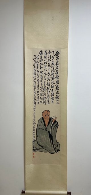 Qi Baishi's vertical axis: The paper is colored with vertical axis, light beige silk mounting and wooden axis. In the lower part of the screen, an ancient monk sitting on the floor is drawn, dressed in a gray-tone monk's robe