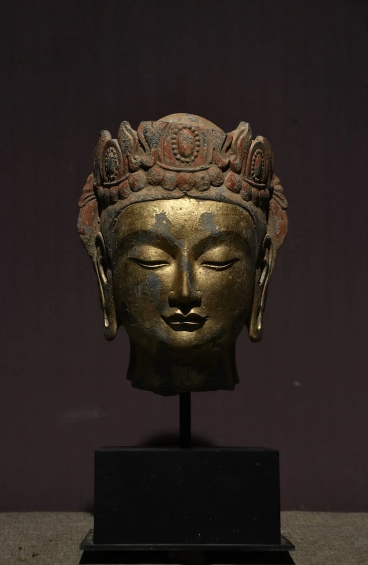 Gold-plated bodhisattva head: Stone carving of the head of a bodhisattva, with a treasure crown, on which there are pearls and lotus petals, and red color remains. The face is covered with gold, the gold layer is partially worn