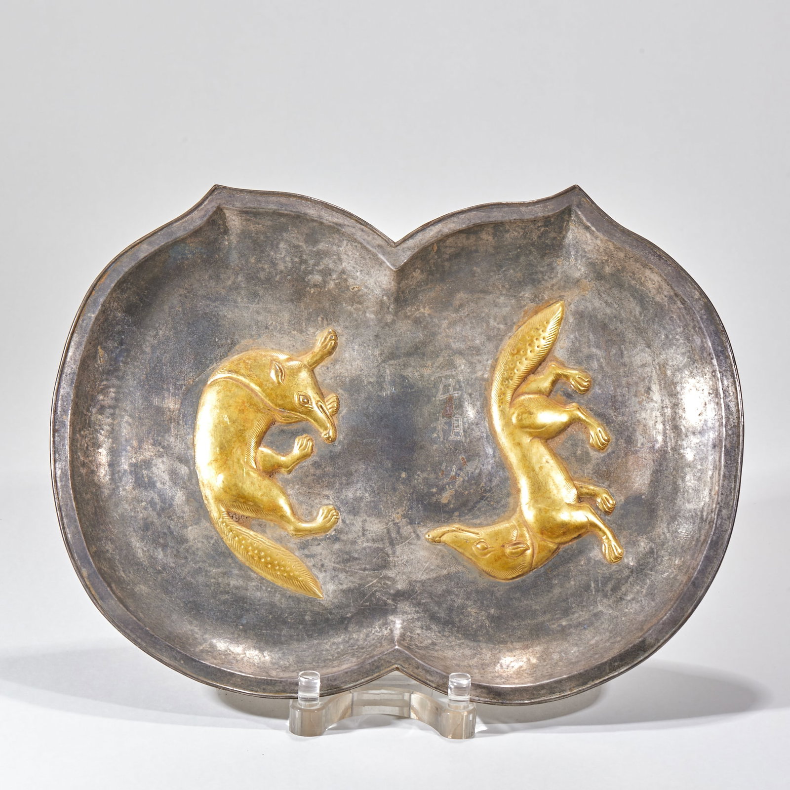 Silver-gilded fox plate: The body is made of double peaches and petals, and the whole body is made of silver. There are two gilded foxes with high relief in the plate. The two foxes are smart, one fox is curled up and looking