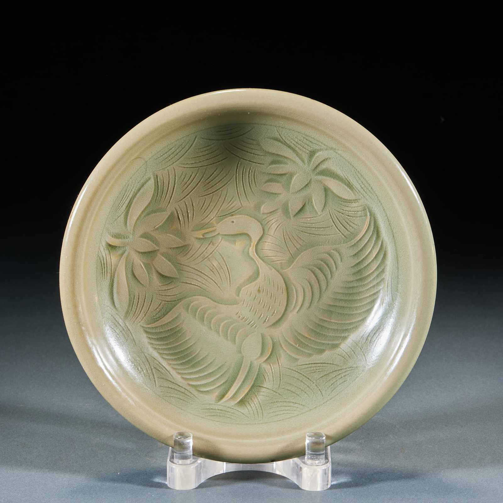 Yueyao crane pattern plate: Open plate, green glaze. The center of the dish is carved with patterns of waterfowl swimming in the lotus pond, waterfowl spreading their wings, and the surrounding area depicts lotus flowers and