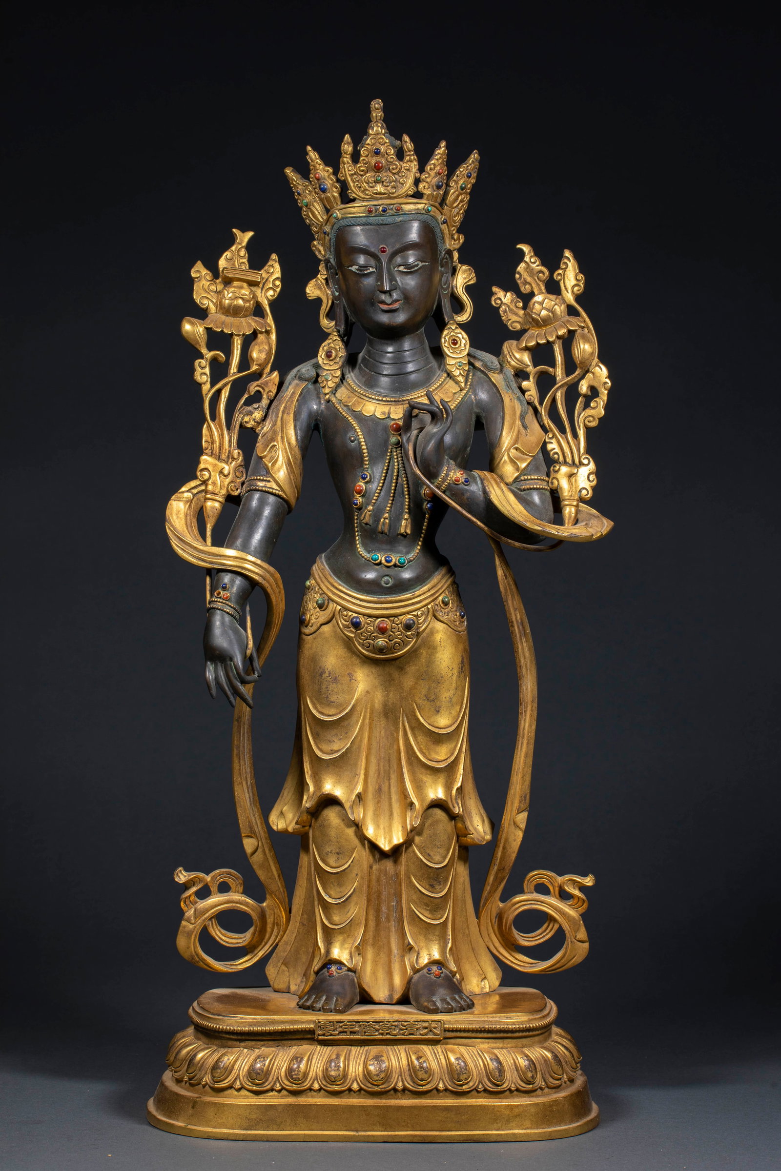 Gilded Bronze Tara Statue, Qianlong Period, Qing Dynasty: Copper-bodied gilded standing figure; the face and torso are of dark copper tone, while the crown, celestial garment, jewelry and lotus base are fully gilded. The bodhisattva wears a five-leaf crown,