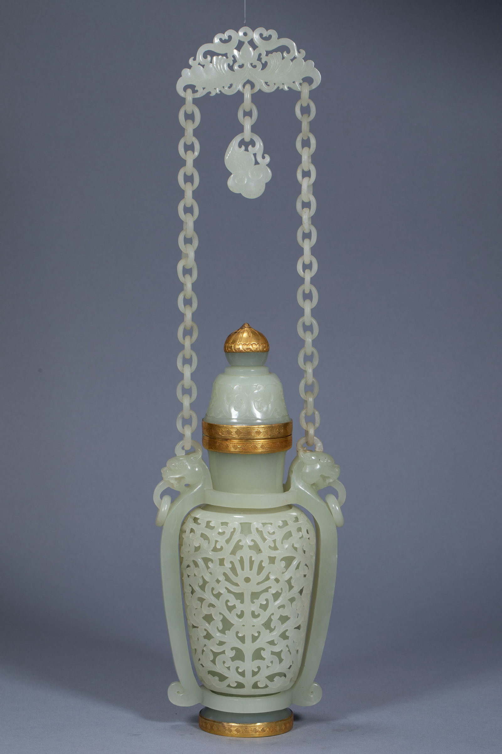 Hetian Jade Openwork-Chained Vase with Gold, Imperial Qianlong, Qing Dynasty: Of Hetian greenish-white jade carved from a single block; the body is pierced with scrolling floral scrolls and carries an integrated chain handle of one-piece movable links. The lid and mouth are set