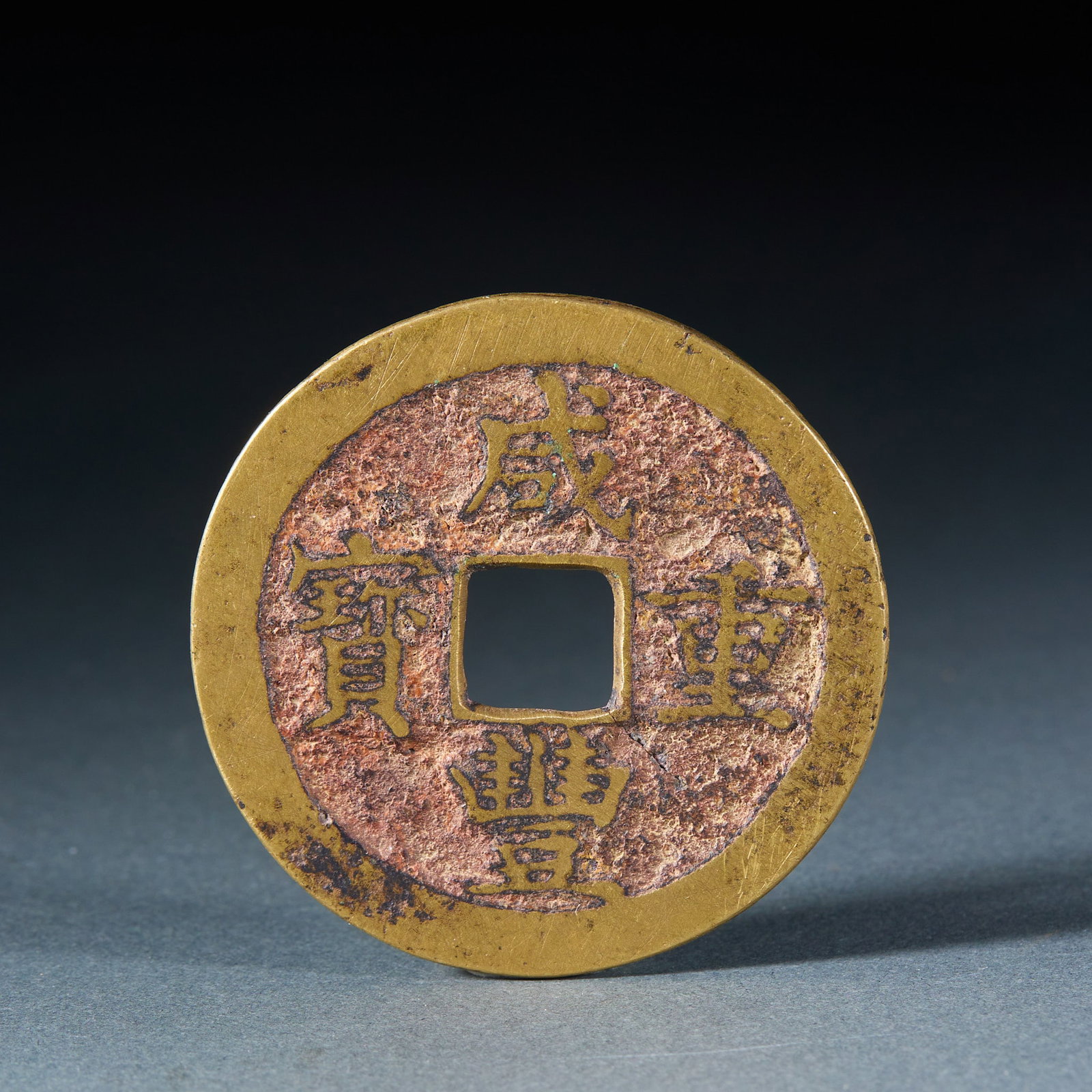Xianfeng Zhongbao 'Dang Shiwu' Charm Coin: Of brass, round with a square hole. The obverse reads 'Xianfeng zhongbao' in regular script read across; the coin is thick and covered with reddish-brown patina. T 0.2 cm, Diameter 5.3 cm, 32 g.