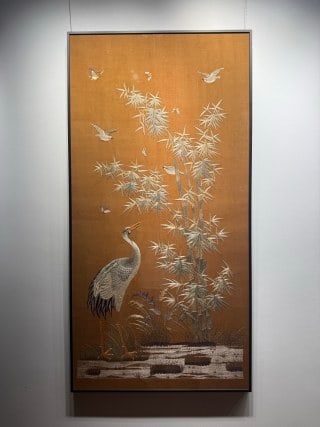 Embroidery of Bamboo, Crane and Spring, Republic Period: A kesi (silk tapestry) work on a tan-yellow ground depicting green bamboo, cranes and flying birds by a waterside; the whole is framed for hanging. L 151 cm, W 76 cm.