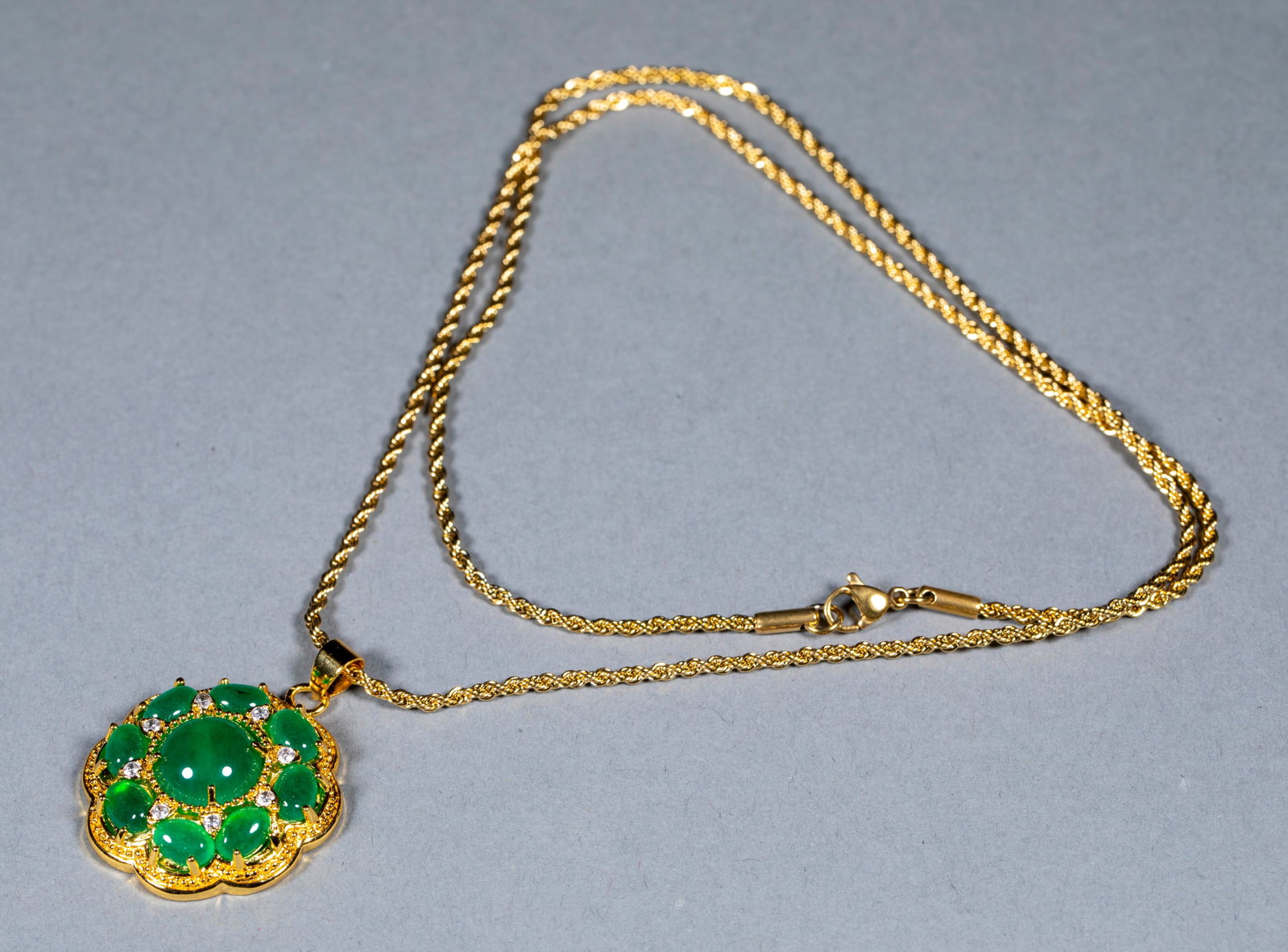 Jewelry Necklace: A gilt twisted-rope necklace whose pendant is a flower-shaped gem-set design: the central stone is a large vivid-green imperial jadeite cabochon encircled by matching jadeite beads, set off by small