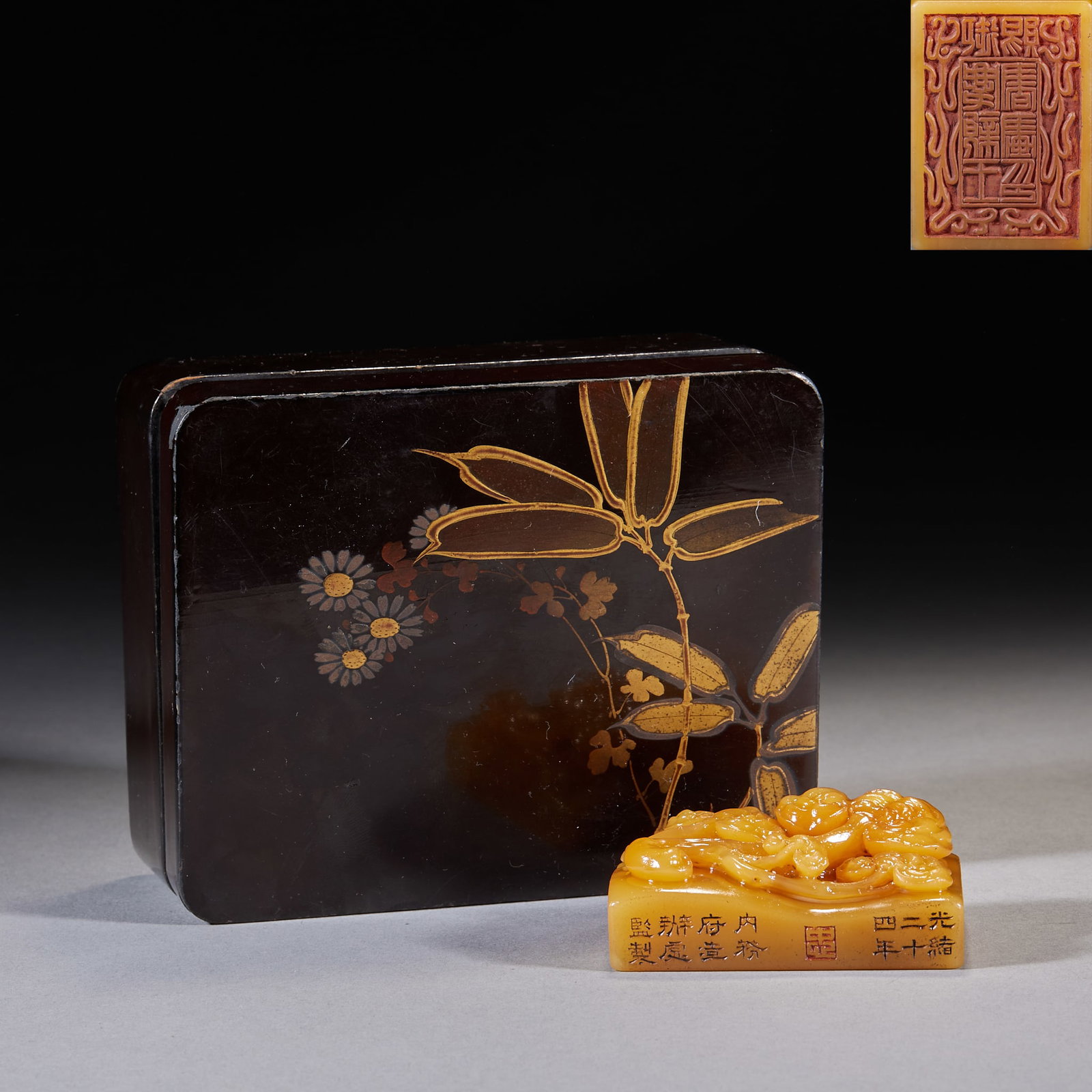 Guangxu 24th-Year Imperial-Granted Tianhuang Stone Seal with Fu-Shou Lingzhi: A square tianhuang seal carved on top with several interwoven chi-dragons; the side bears an inscription and a corner carries an impression. Supplied with a Japanese maki-e lacquered wood box painted