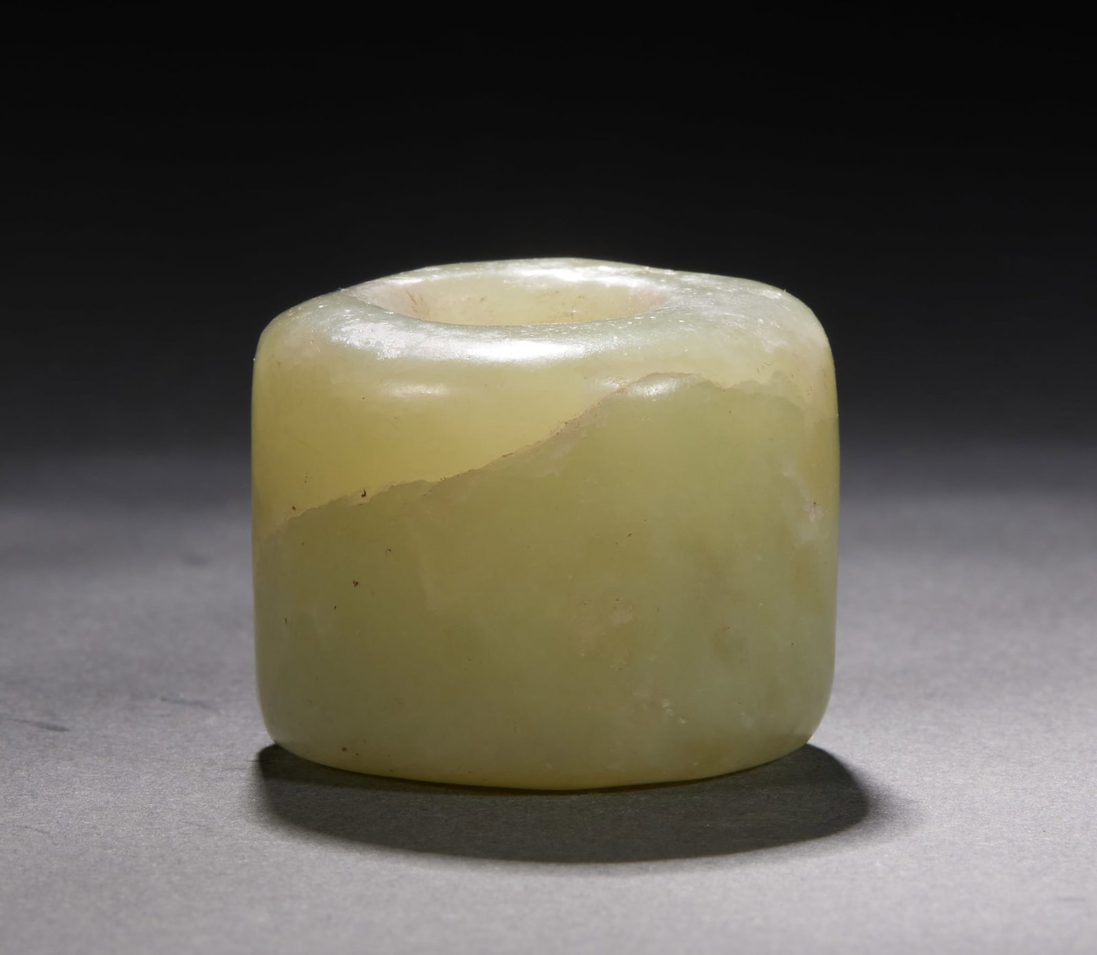 Hongshan Jade Cong: A straight-tube thumb ring of yellowish-green jade with natural mottling and weathering. The form is archaic and sturdy with thick walls; originally a finger guard for archery, it later became a