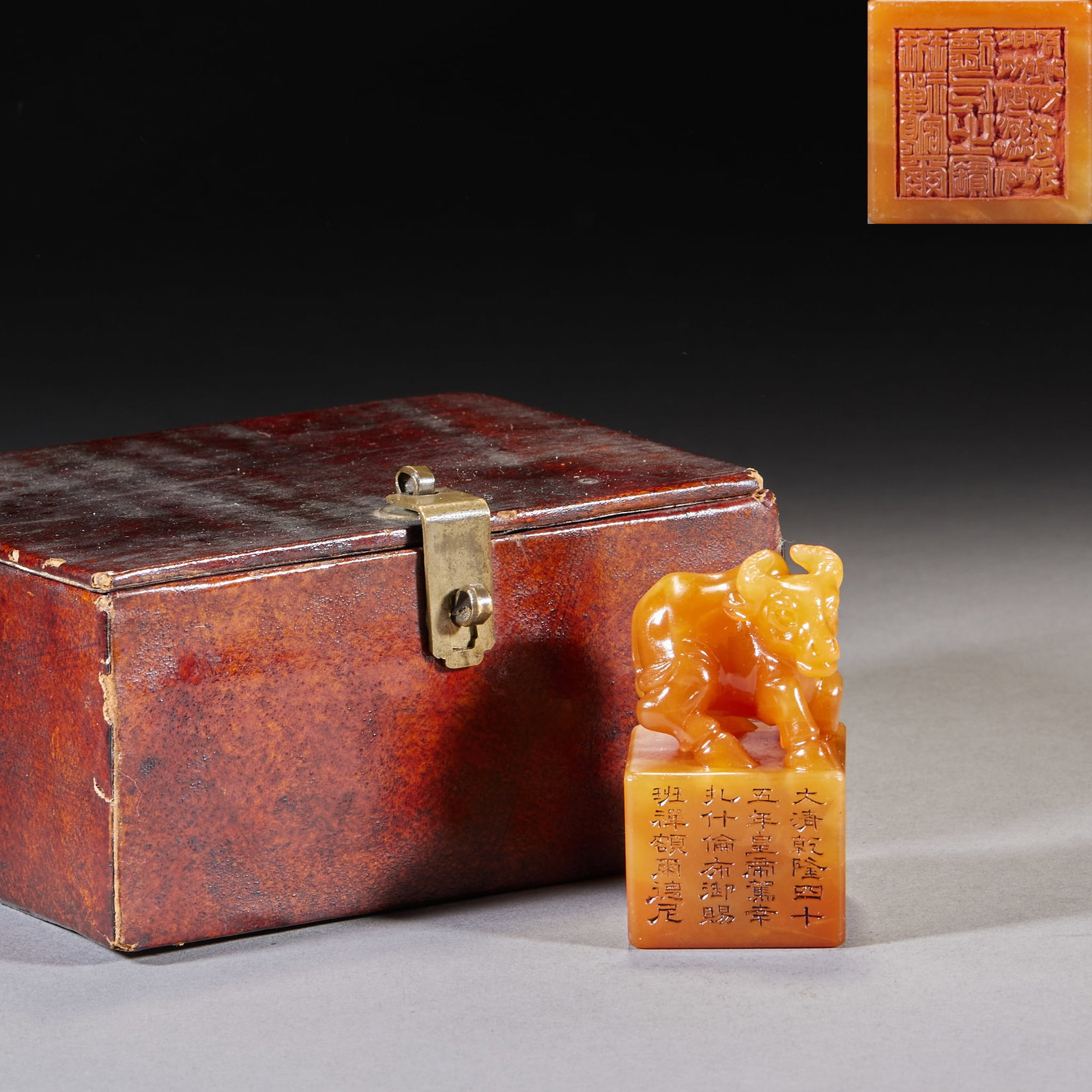 Panchen Erdeni 'Qi Chong Dou Niu' Tianhuang Stone Seal: A square Shoushan tianhuang seal carved on top with a reclining-ox knop, honey-yellow and warm. The side bears a border inscription recording an imperial gift of the 45th year of Qianlong; the seal