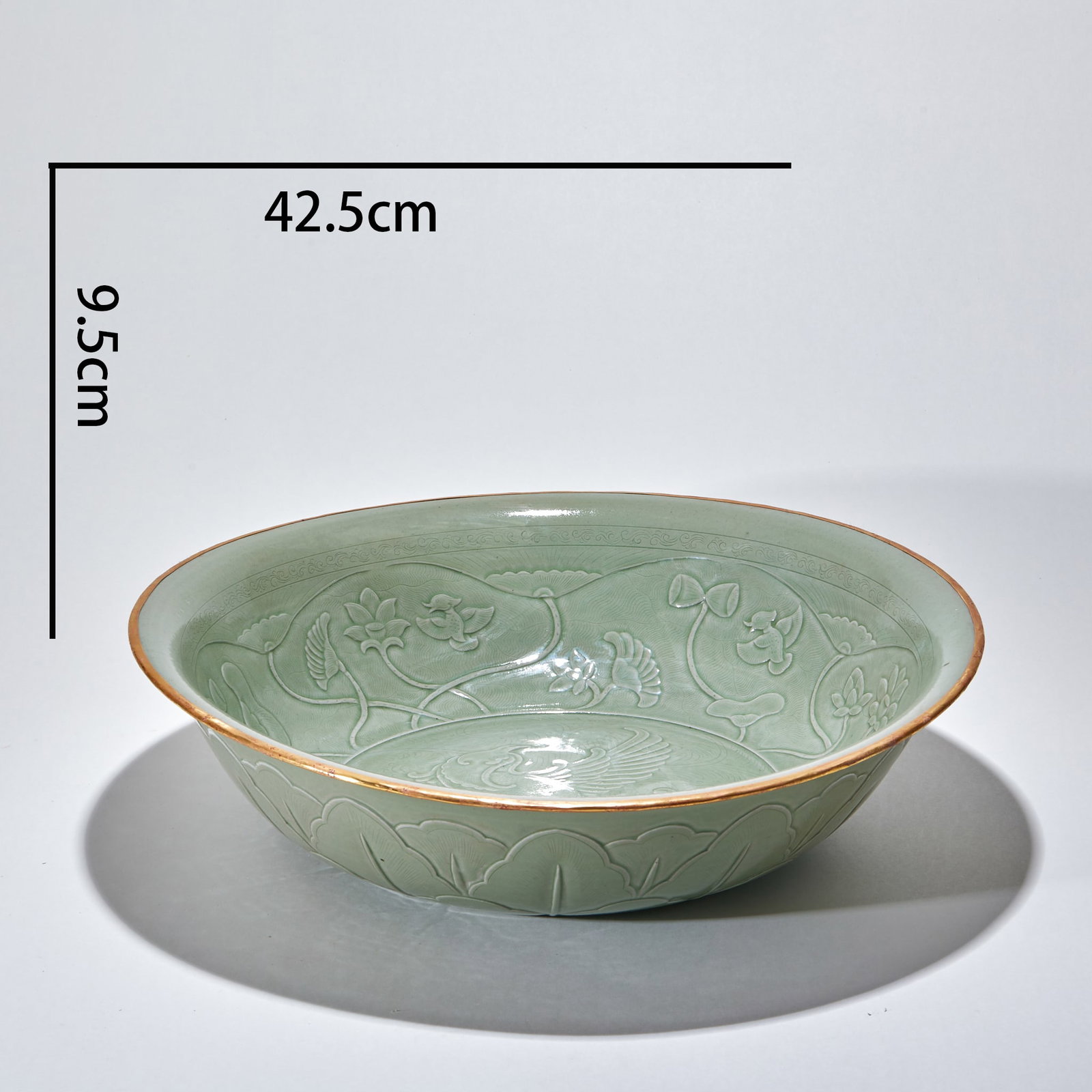 Yue Kiln Gold-Rimmed Phoenix Dish: The rim is wrapped in gold; inside is carved a scene of mandarin ducks playing in a lotus pond, and the exterior in relief with lotus-petal bands. A large Longquan celadon bowl for display. H 9.5 cm, 