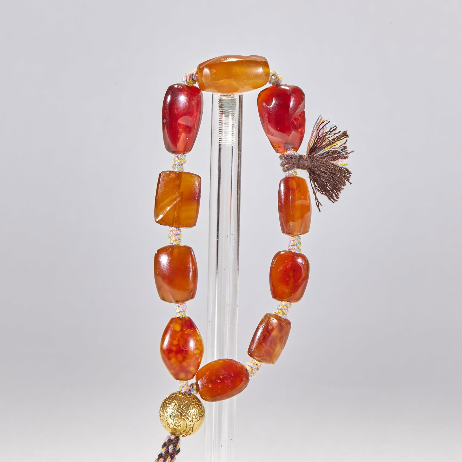 Pre-Ming Agate Bracelet: Strung of many old irregular agate beads with engraved gilt beads and a tassel at the end. The agate is reddish-brown and archaic ?? an old-bead personal ornament. Single bead L 2.2 cm, W 1.5 cm, T