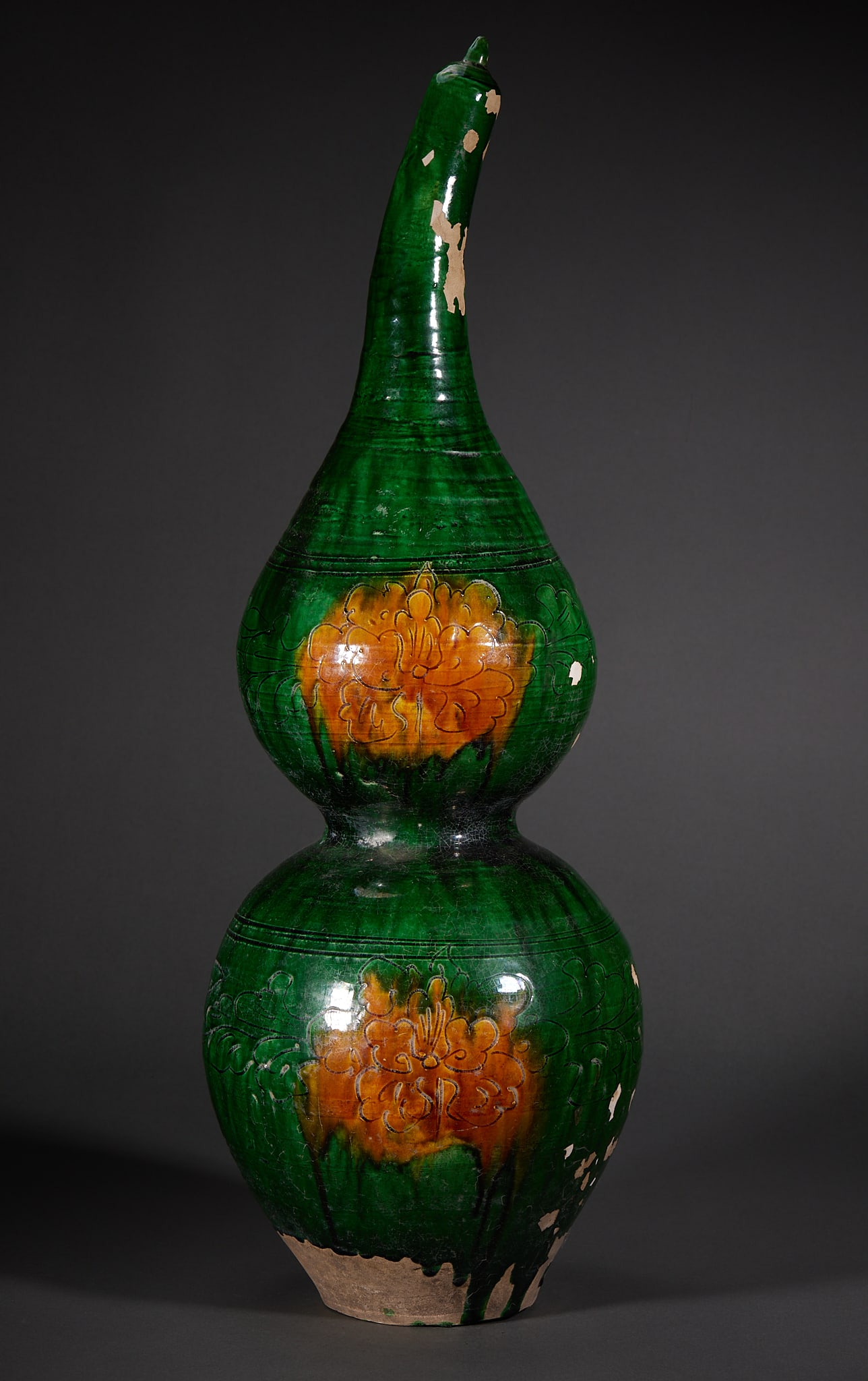 Green-Glaze Gourd Vase: A green-glazed earthenware gourd vase with carved floral decoration and patches of yellow-brown colour. The gourd form symbolises good fortune and rank. H 60.5 cm, Diameter 18.5 cm.