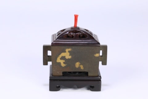 Qing 'Treasure of the Family' Gold-Splashed Horse-Trough Bronze Censer: A square bronze censer with flanged double ears, the body decorated with splashed-gold specks, fitted with an openwork wood cover, coral finial and wood base. Imitating the Ming Xuande burner form; a