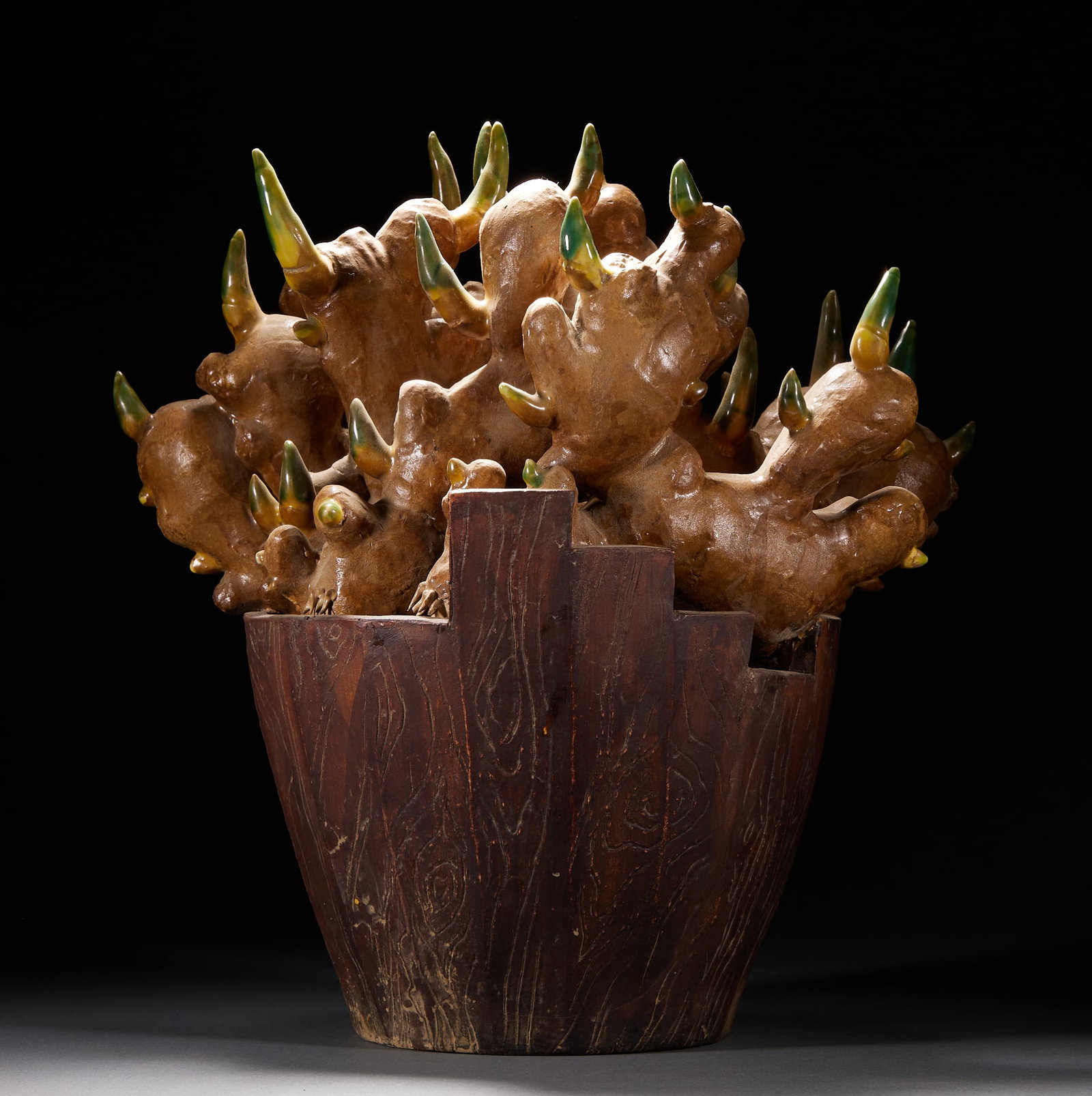 Unified Rivers-and-Mountains Ornament: A bogus-ware piece imitating a clump of ginger: the shoots glazed green-yellow, set in a wooden basin. Bogus-ware was a distinctive Qing craft in which porcelain imitates real objects with remarkable