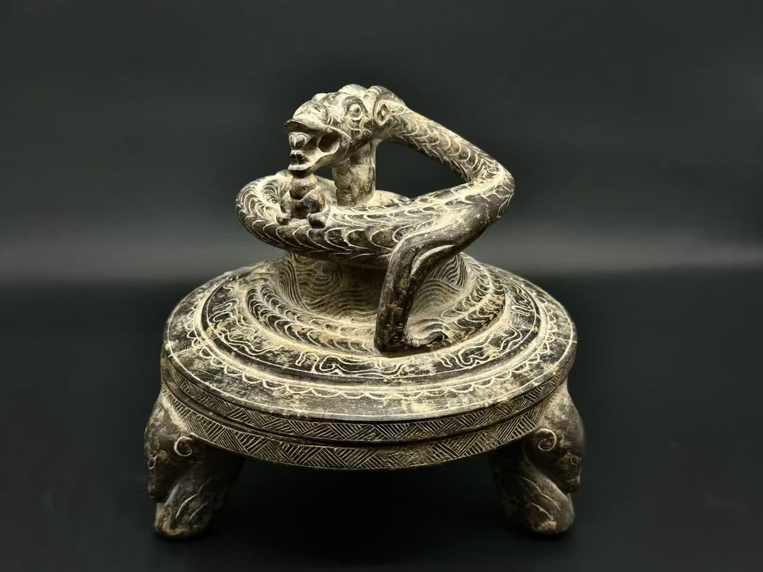 Grey-Stone Coiled-Dragon Inkstone: Carved from black stone on a three-footed beast-form base; the cover bears a coiling jiao-dragon with raised head, the cover densely carved with wave and meander patterns of complex layering. A major