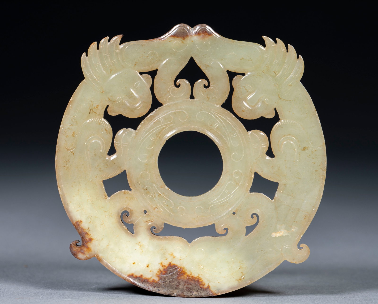 Openwork Auspicious-Beast Jade Bi: Of Hetian greenish-white jade with reddish-brown calcification. Twin chi-dragons are carved in openwork encircling a small central bi, their bodies curving gracefully. A Han pendant jade cut by