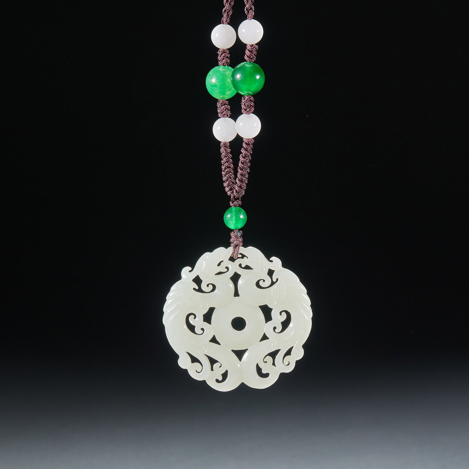 Jade Twin-Phoenix Pendant: Of warm pure white jade, cut in openwork: a central bi disc flanked by twin phoenixes with fluid, graceful lines ?? a traditional auspicious jade pendant. Strung with jadeite and white-jade beads, the