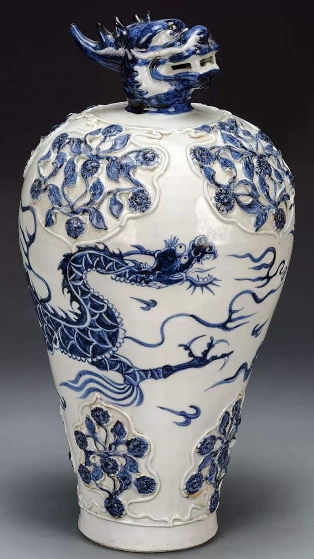 Underglaze-Blue Auspicious-Cloud Dragon Prunus Vase with Dragon-Head Cover: An underglaze-blue meiping whose mouth is modelled as a three-dimensional dragon head as cover; the body is painted with underglaze-blue dragons, and the shoulder bears applied relief panels of cut