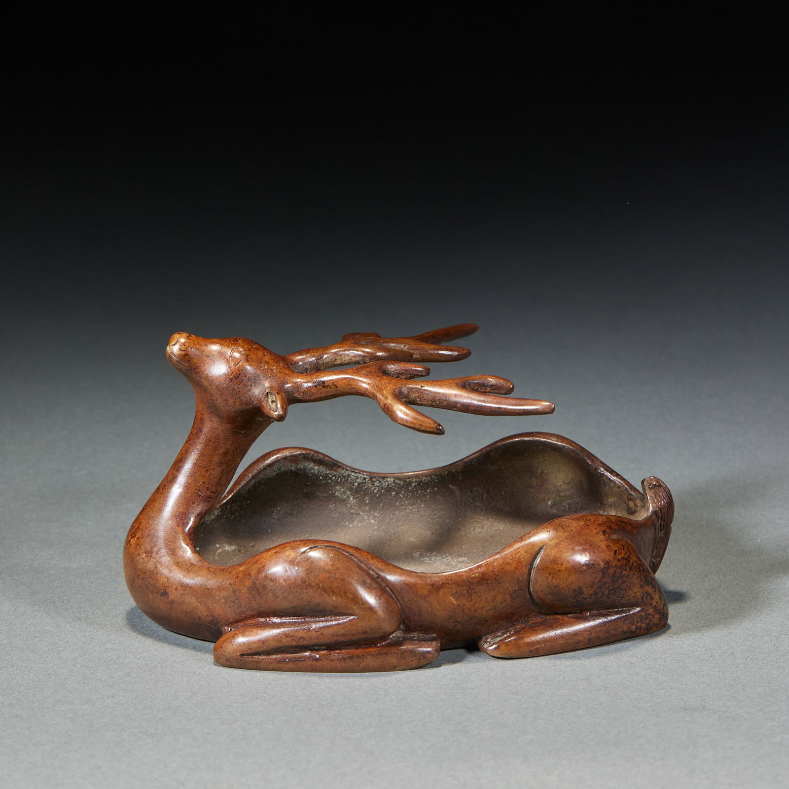Copper 'Lulu Tong' Brush Washer: Cast in old bronze as a reclining deer with a hollowed body forming the water container, antlers spread, serene posture. The skin has a jujube-red patina. A scholar's piece to hold water and brushes.