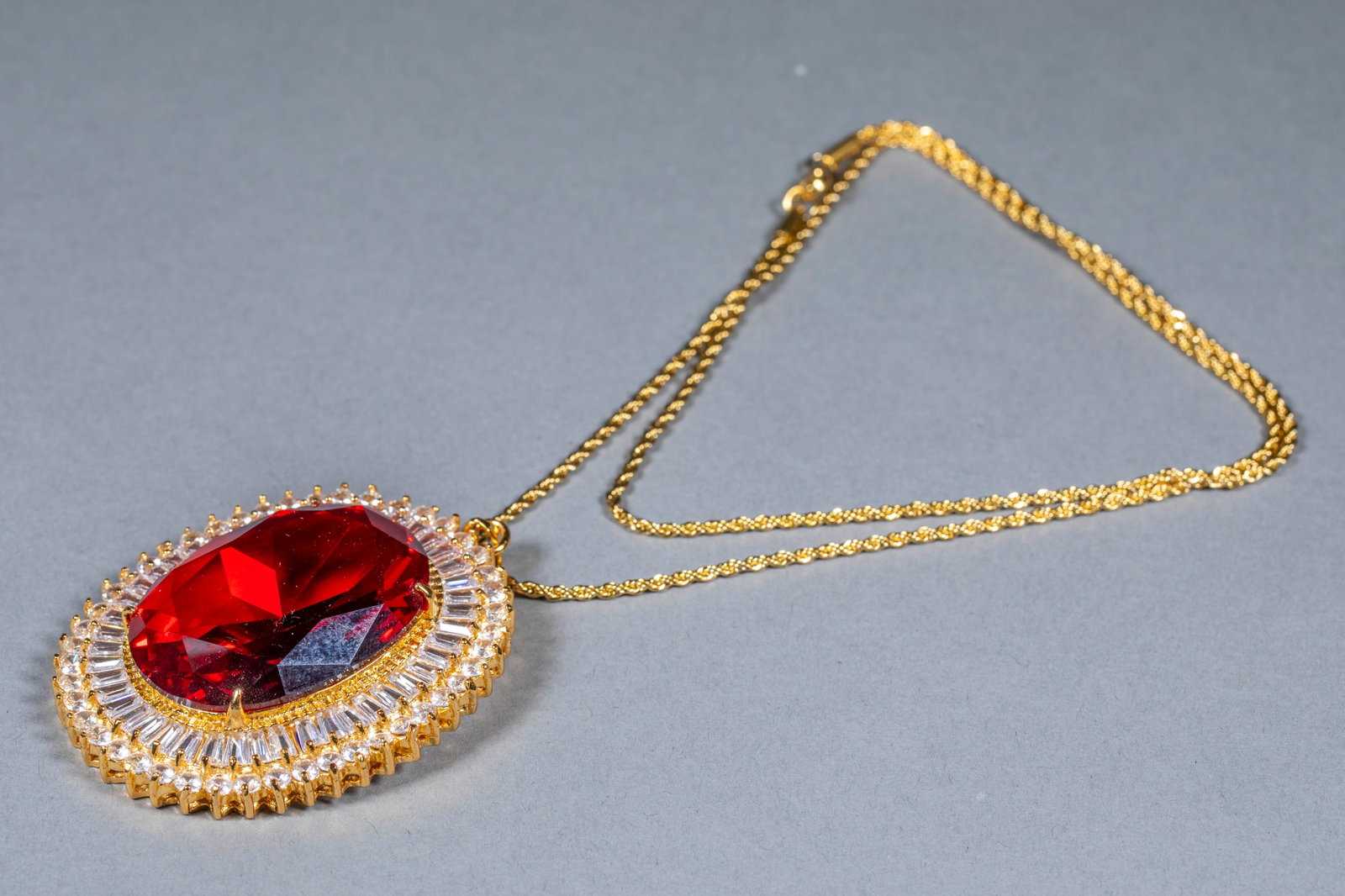 Jewelry Necklace: A twisted-chain necklace whose pendant is a large oval ruby principal stone surrounded by double rows of rectangular-cut white diamonds. H 1.5 cm, L 6 cm, W 5 cm, 48 g.